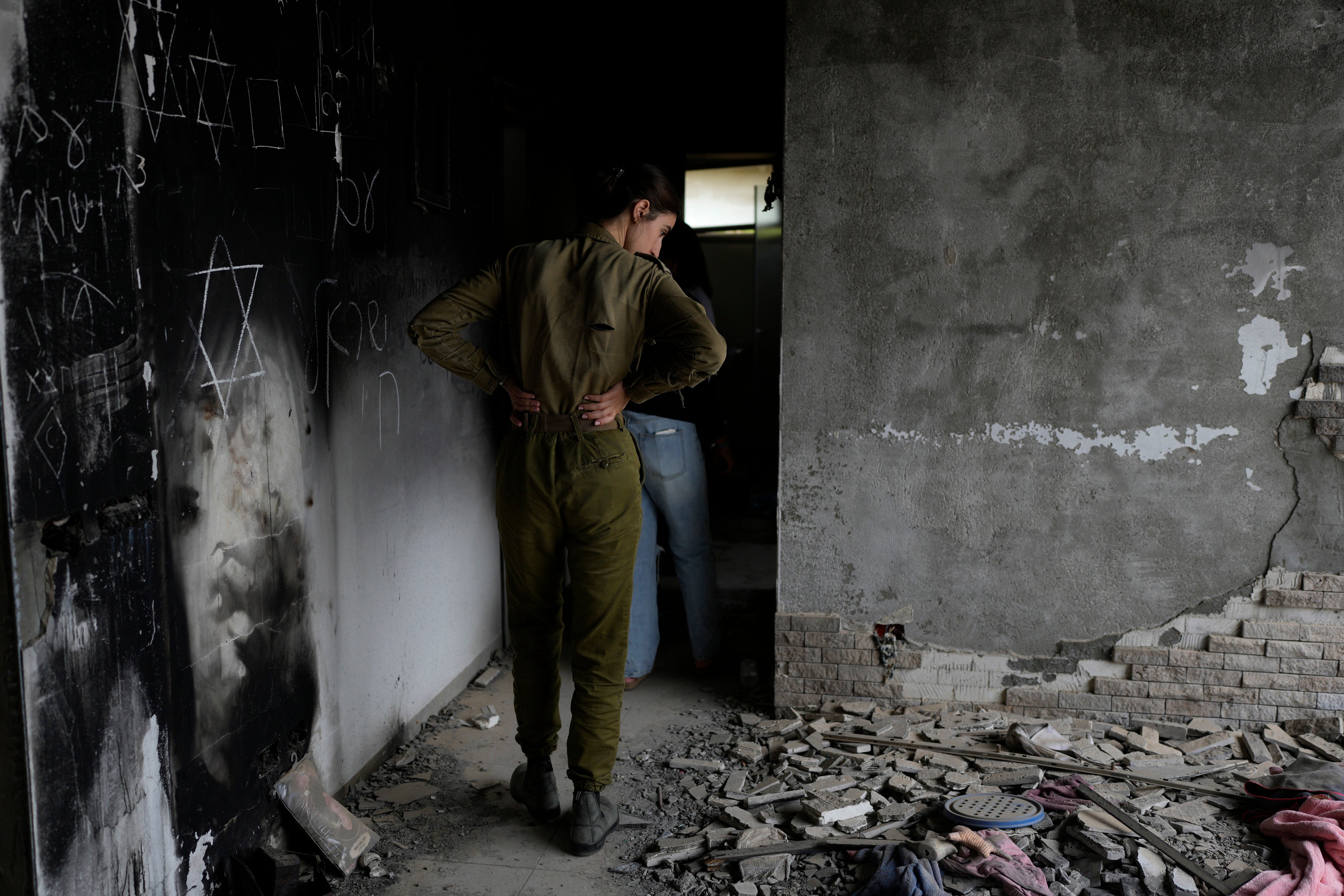 An Israeli soldier looks at a battle scarred home in Kibbutz Be’eri