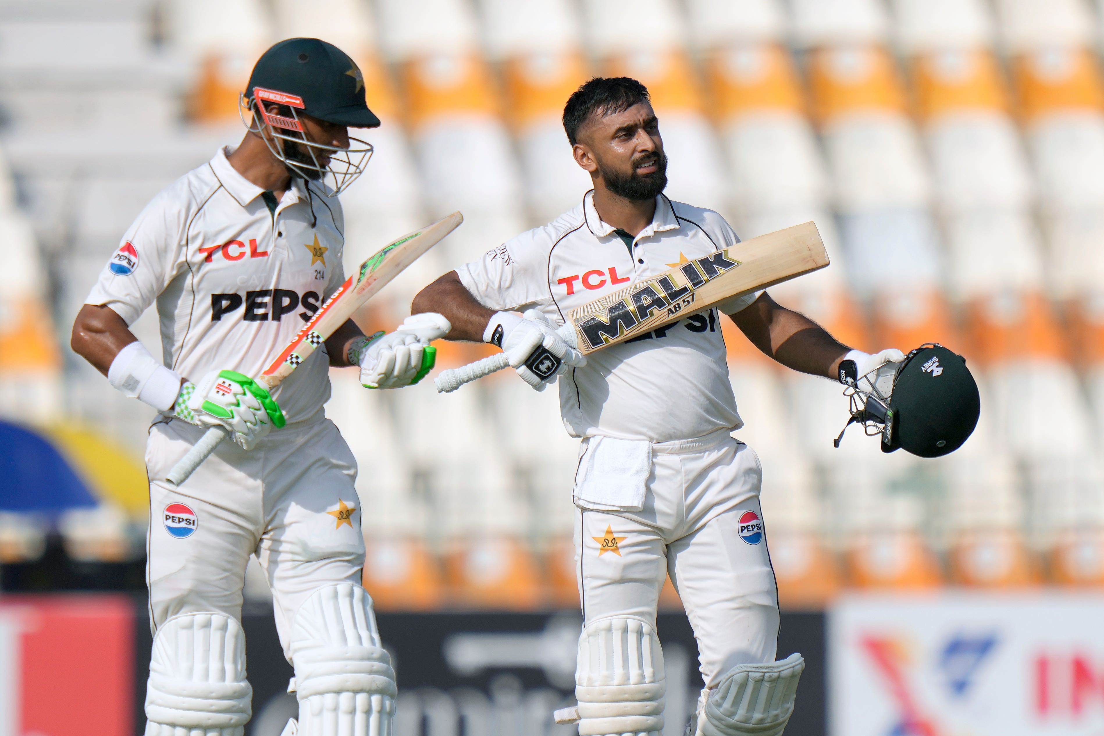 Pakistan’s Abdullah Shafique, right, celebrates with teammate Shan Masood after scoring a century