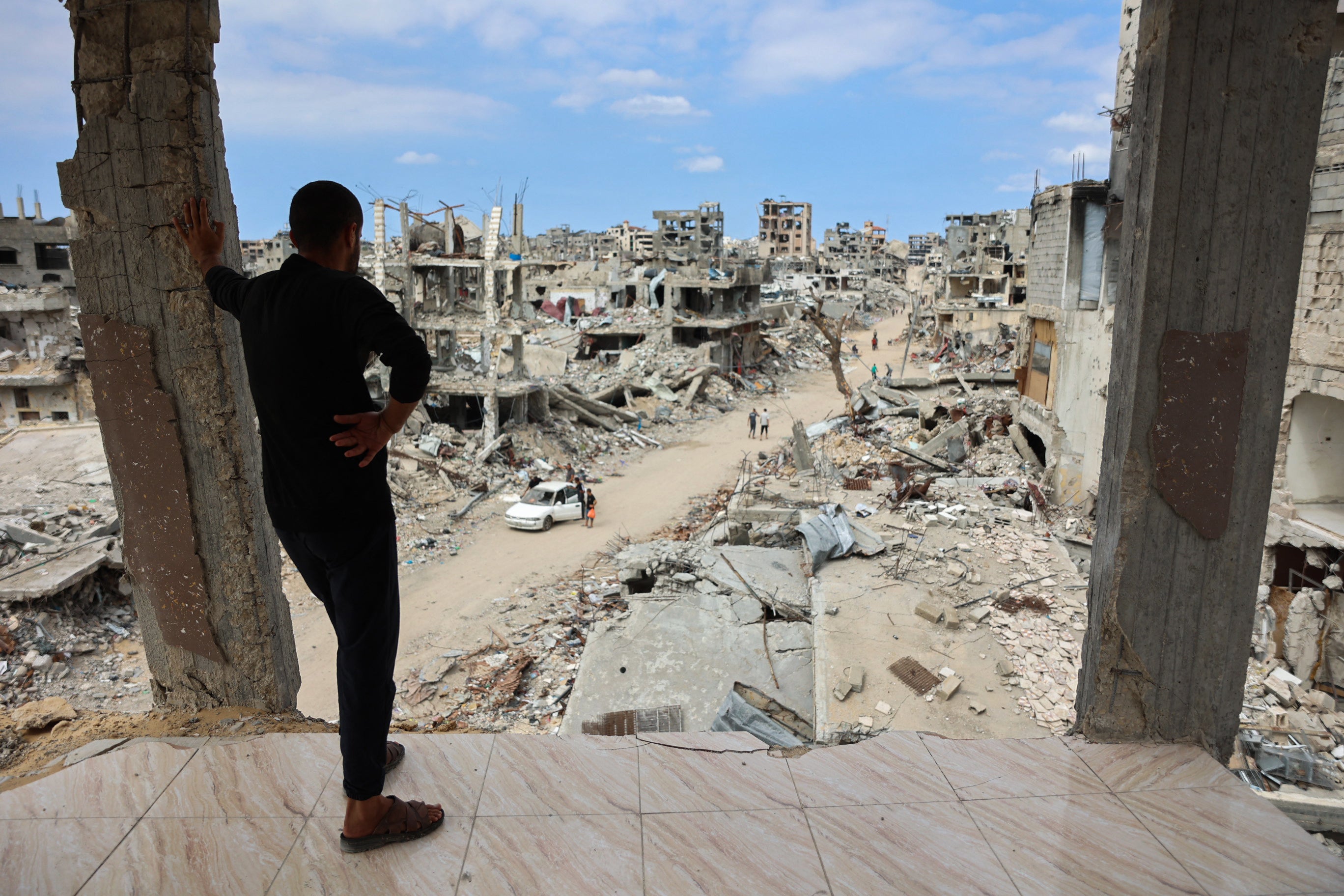 A Palestinian man looks from a damaged building at a dirt road lined with rubble in the Shujaiya neighbourhood of Gaza City