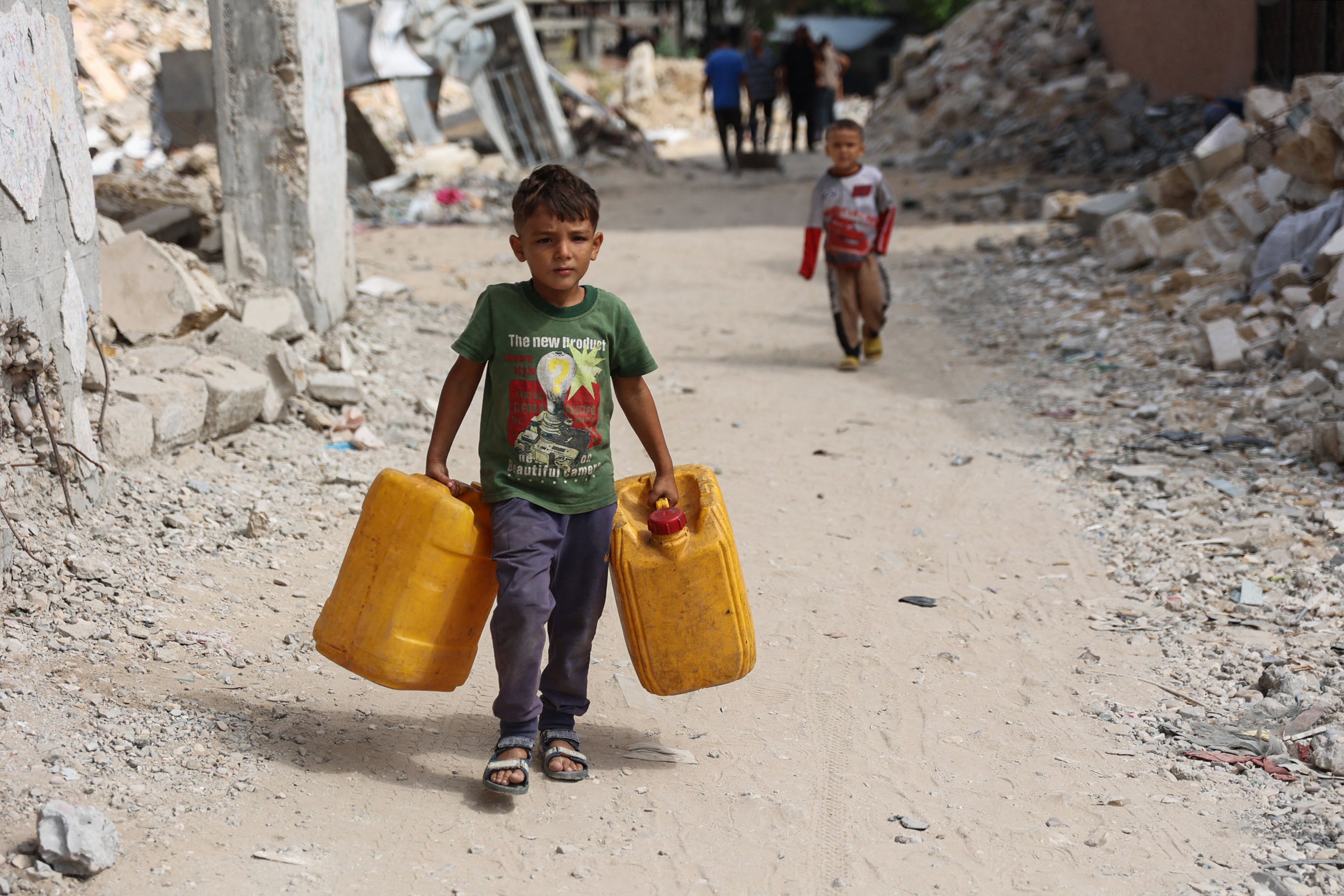 Displaced Palestinian youths carry containers to ferry water from a distribution point in the Shujaiya neighbourhood of Gaza City