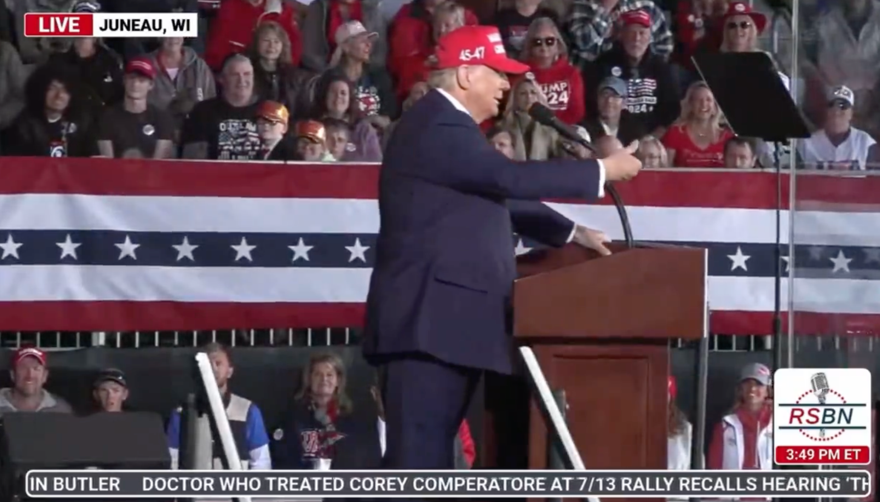 Trump tries to swat away a fly while making an address at a Juneau, Wisconsin, rally on Sunday