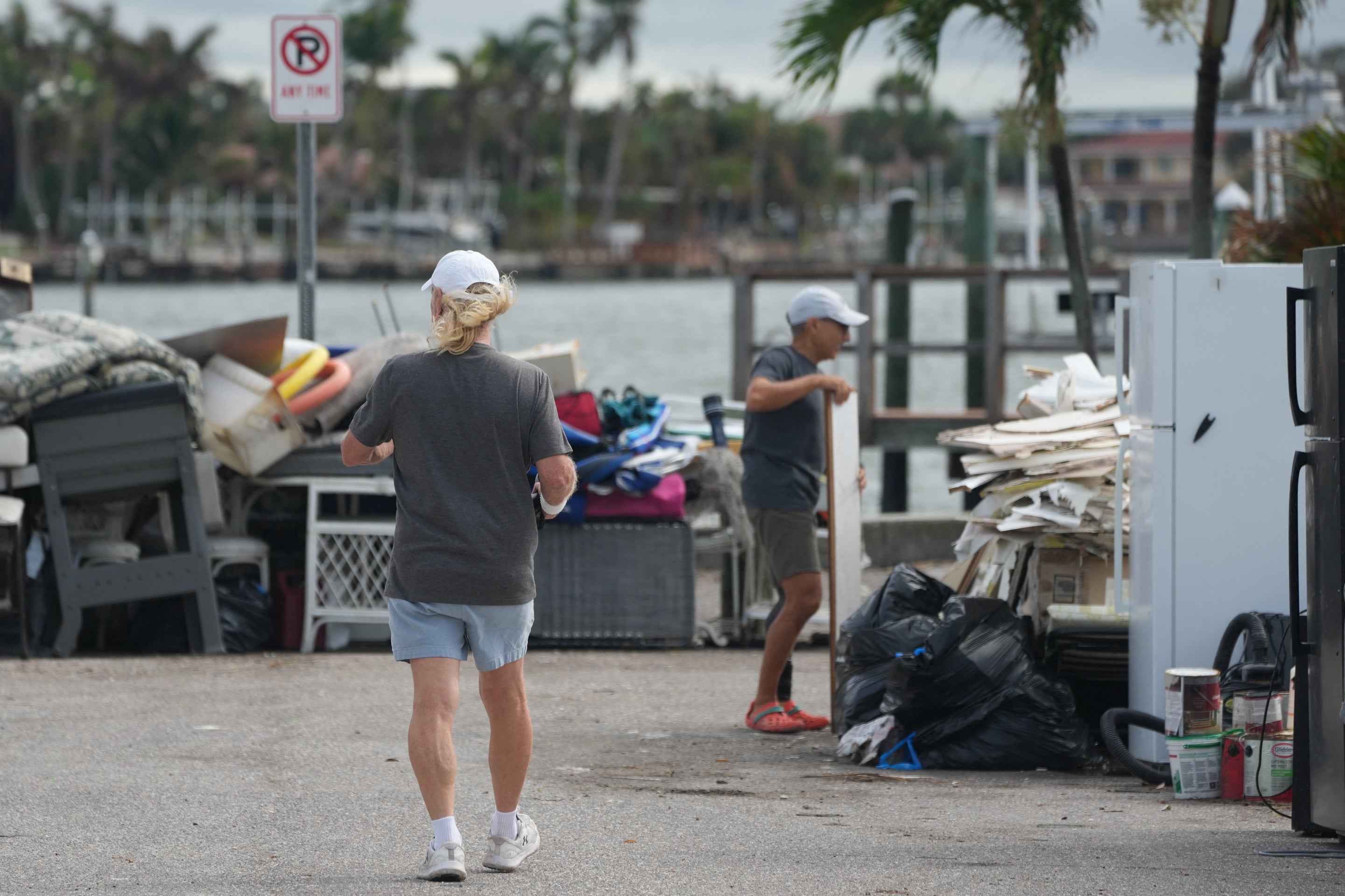 Residents carry debris left by Hurricane Helene out to the street ahead of Hurricane Milton's expected landfall in the middle of this week in Treasure Island