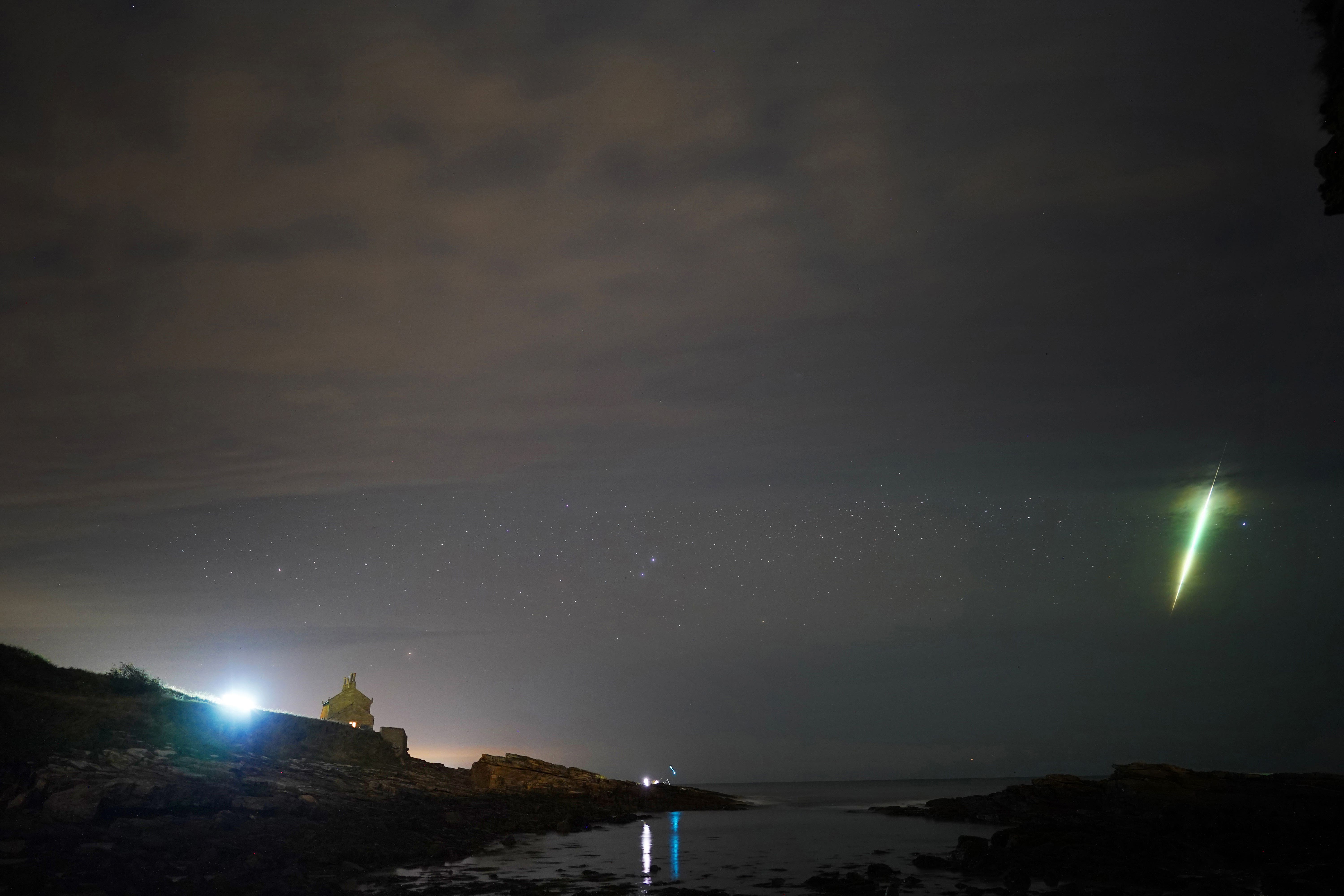 A fisherman watches on during the Draconid meteor shower over Howick rocks in Northumberland in 2021 (Owen Humphreys/PA)