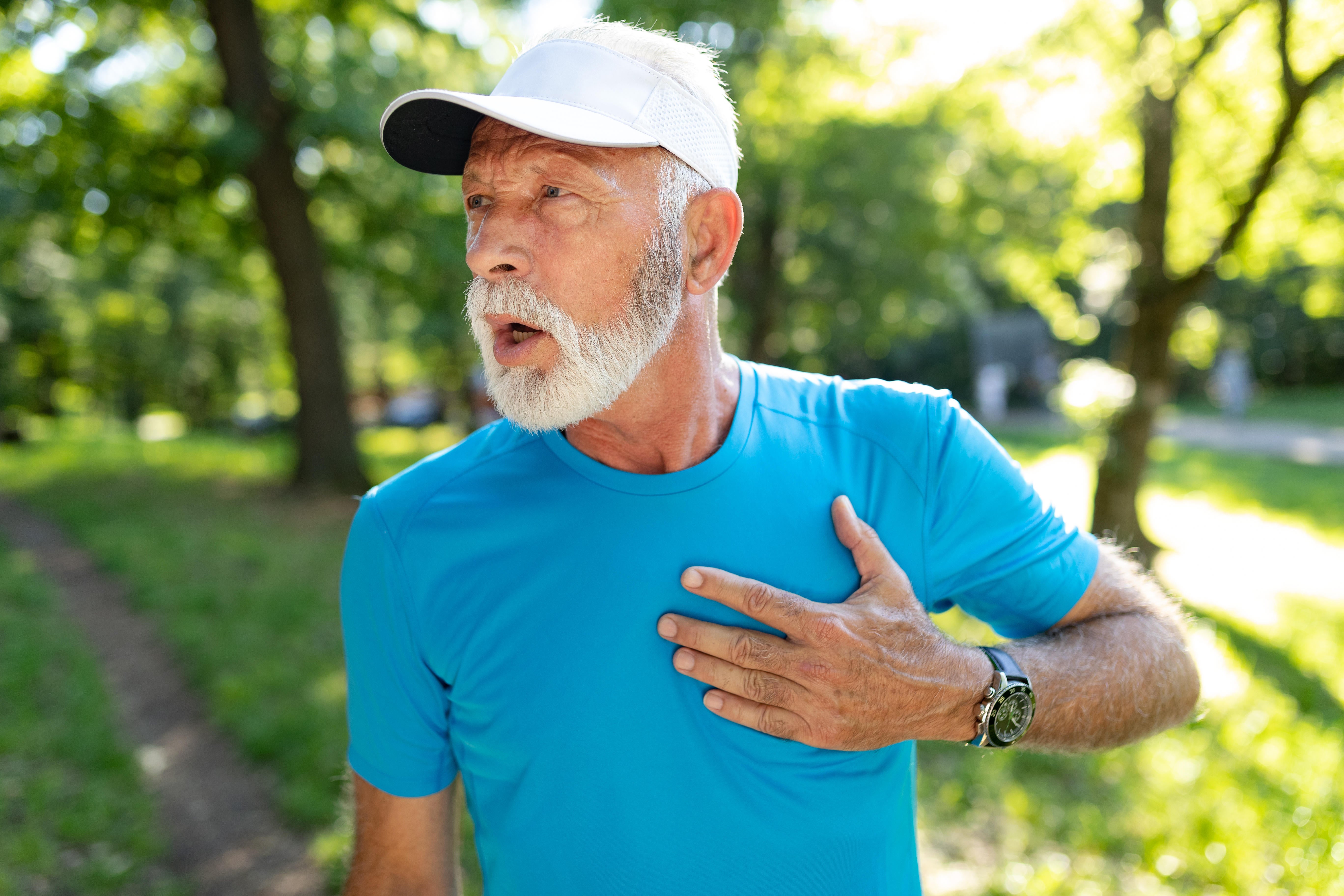 Senior man with chest pain suffering from heart palpitations while jogging