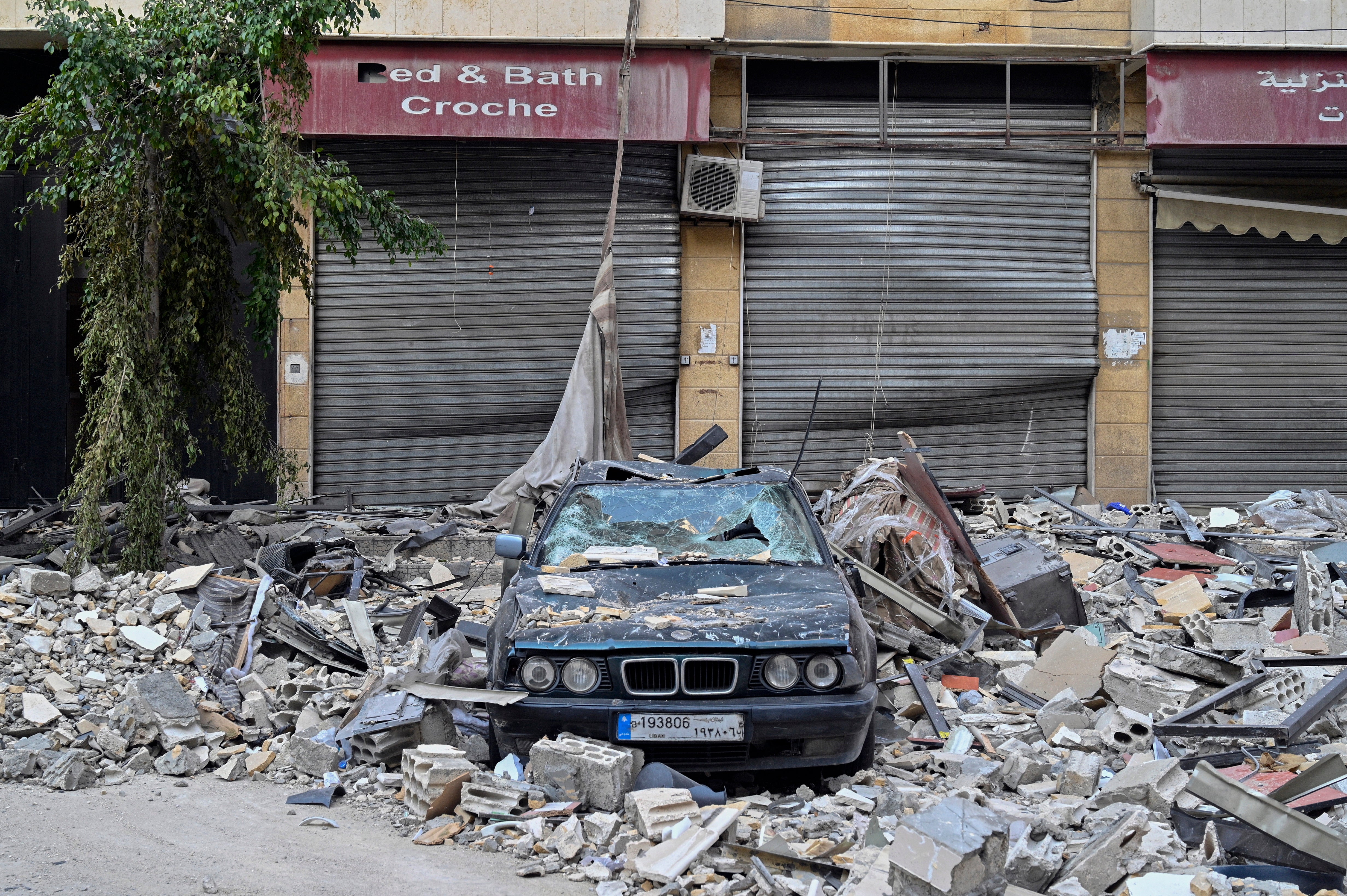 A car flattened by rubble sits outside a shop in Beirut