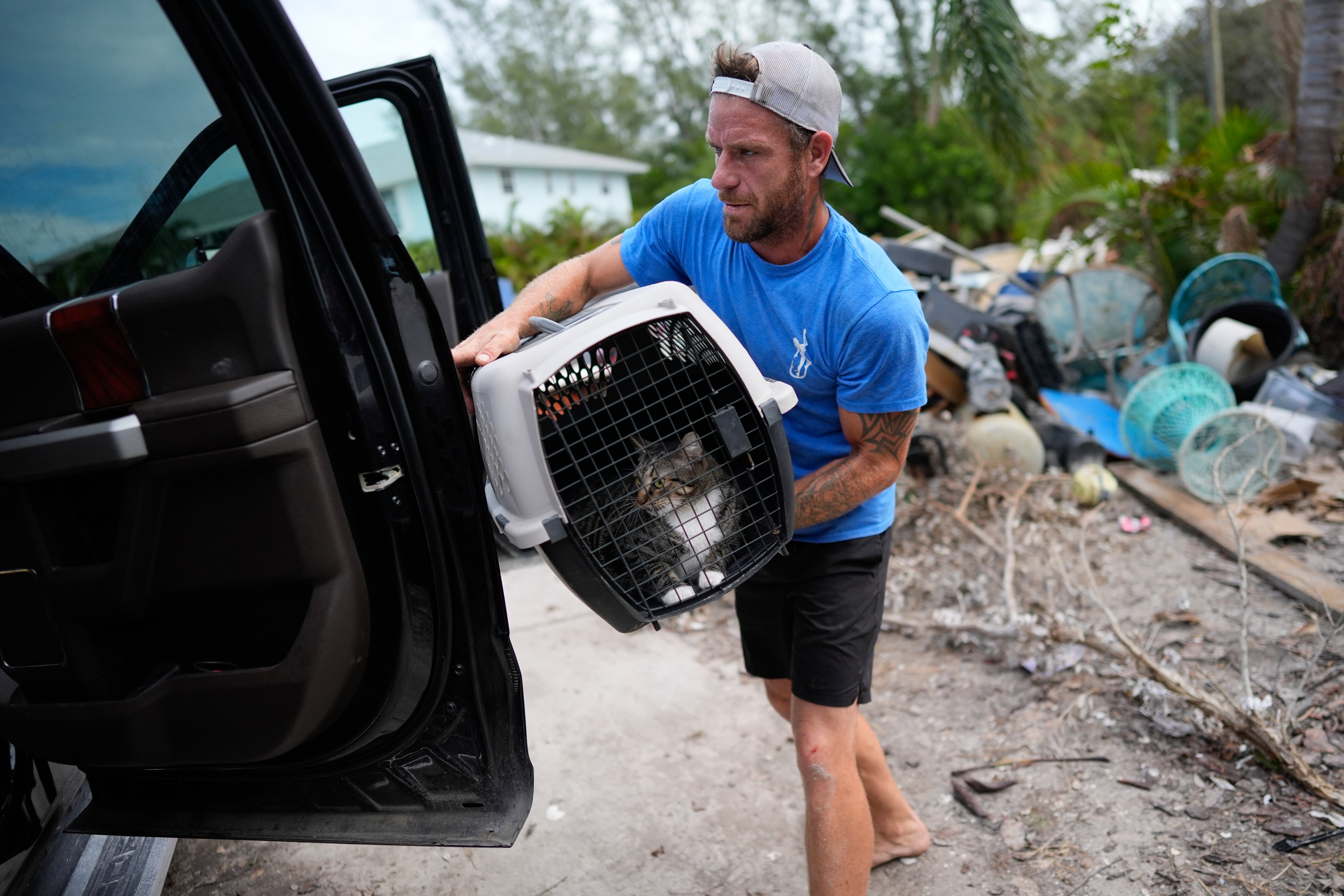 Ted Carlson puts his best friend Evan Purcell's cat McKenzie into a pick-up truck on Anna Maria Island, as the pair evacuate ahead of Hurricane Milton on Tuesday. The area had been hit hard by Hurricane Helene just days prior.