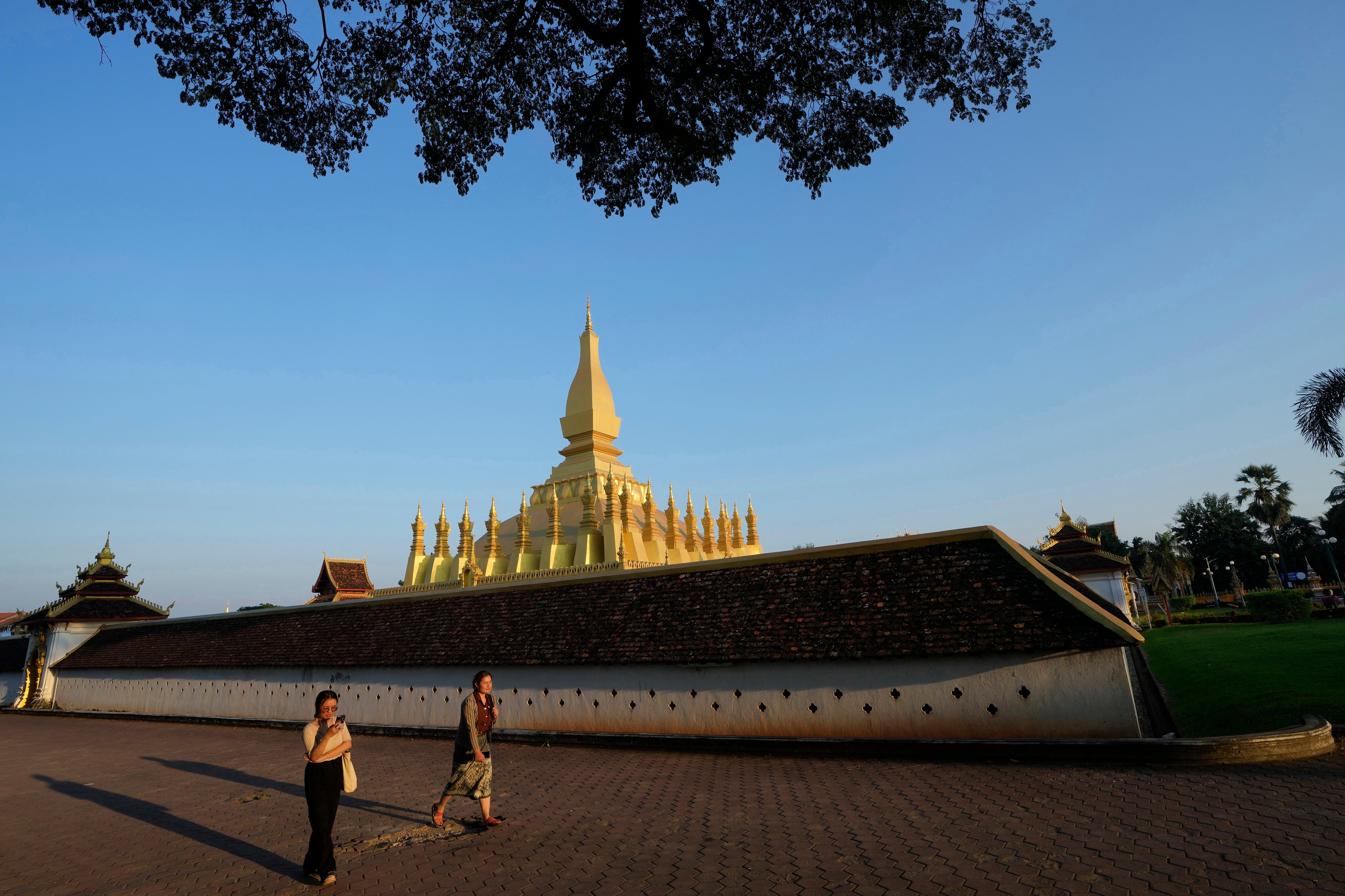 People walks outside Pha That Luang T temple in Vientiane, Laos