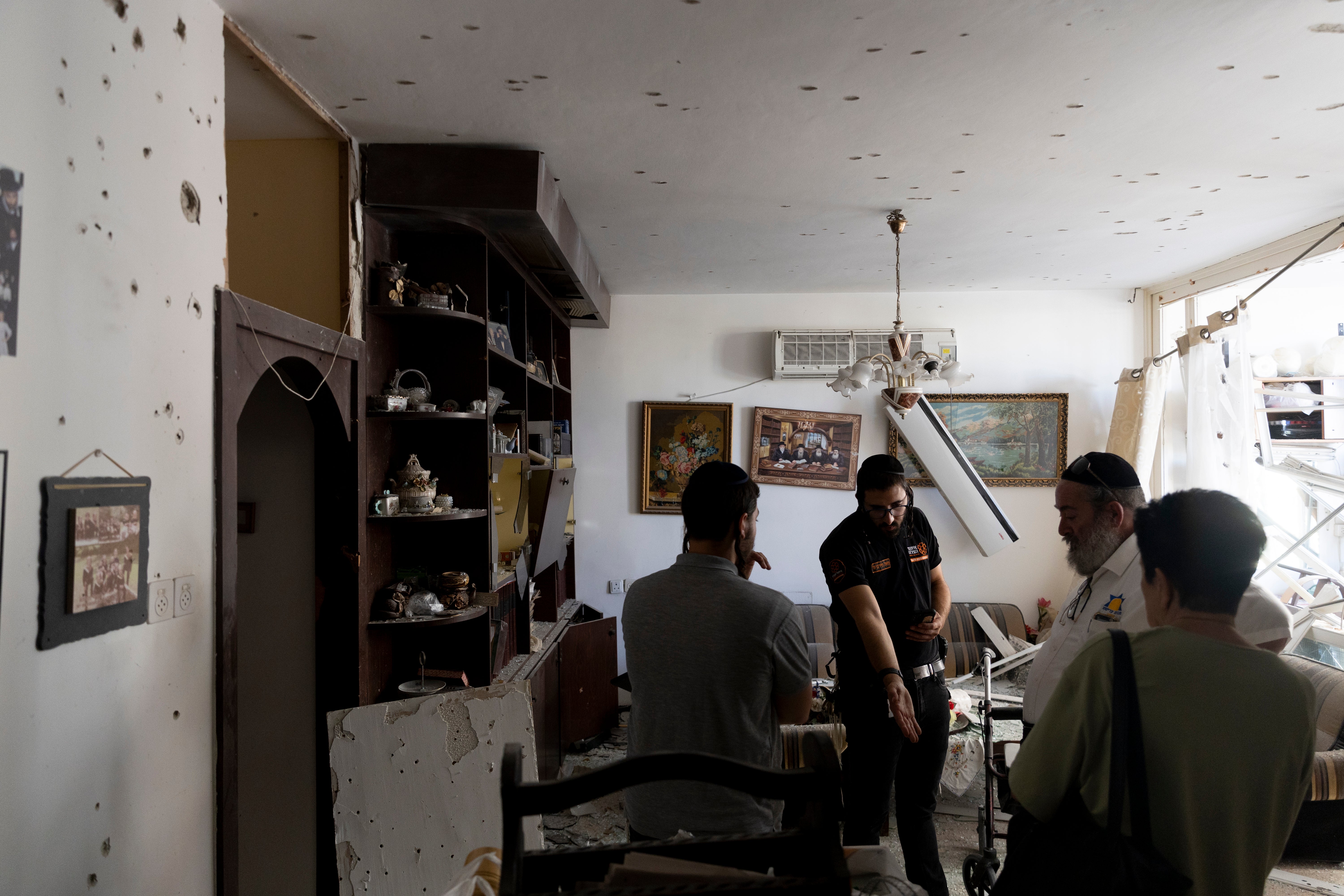 Residents inspect damage on a residential building hit by a rocket fired from Lebanon in Kiryat Yam near Haifa, Israel