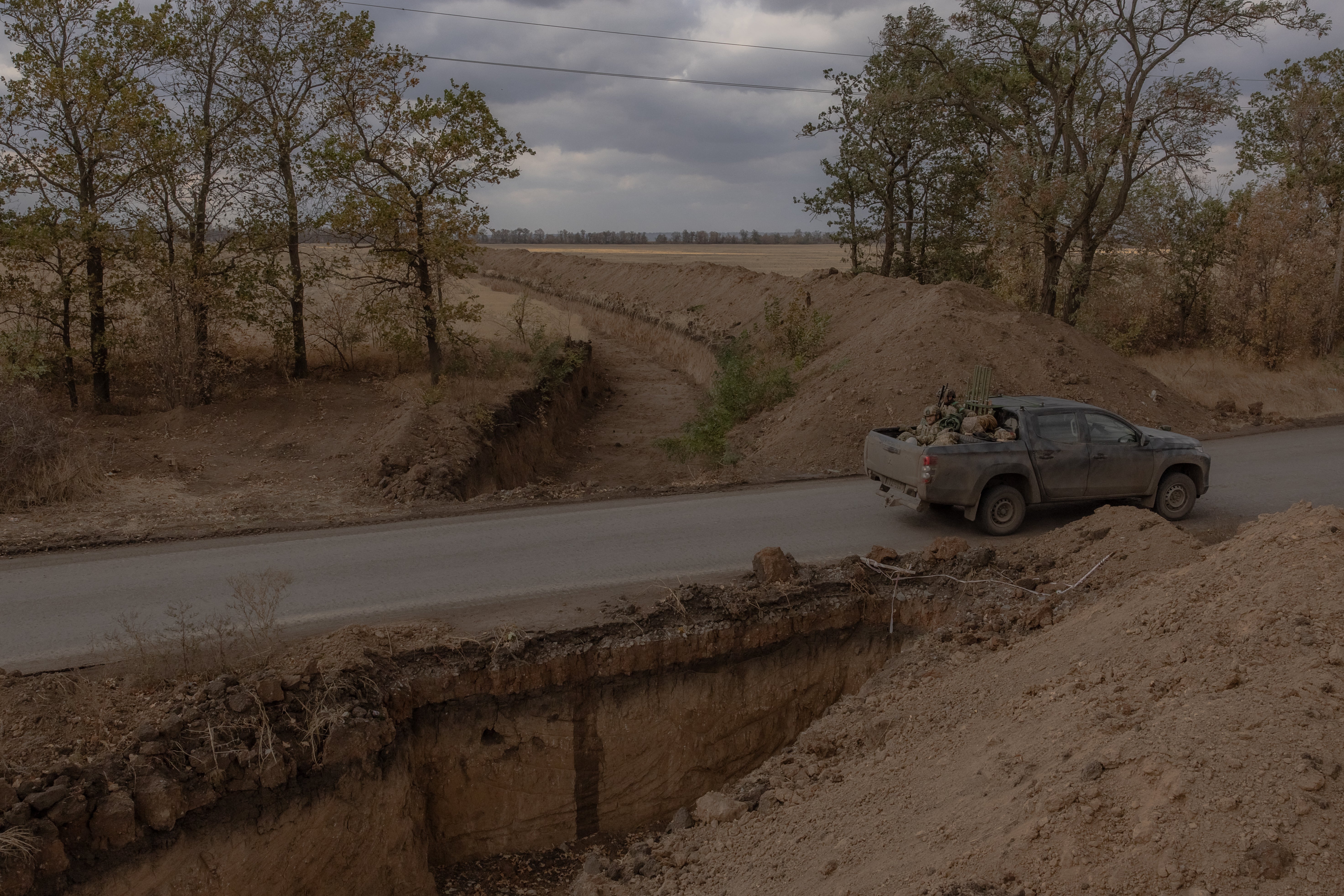 Ukrainian servicemen drive past a large trench prepared by the Ukrainian army in the Vuhledar direction of the eastern Donetsk region