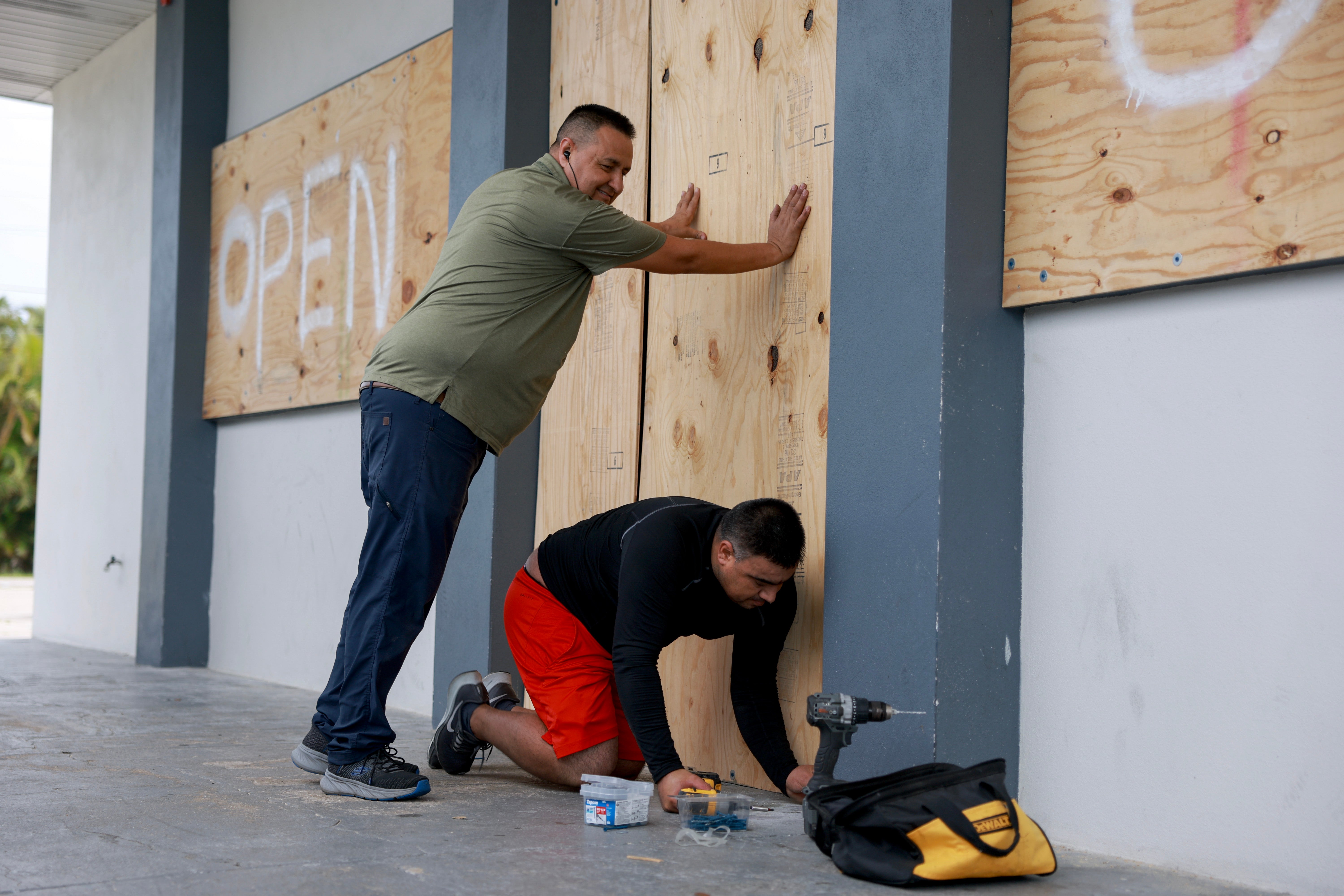 Fort Meyers residents board up a building in preparation for Hurricane Milton, which is expected to bring storm surge up to 15 feet