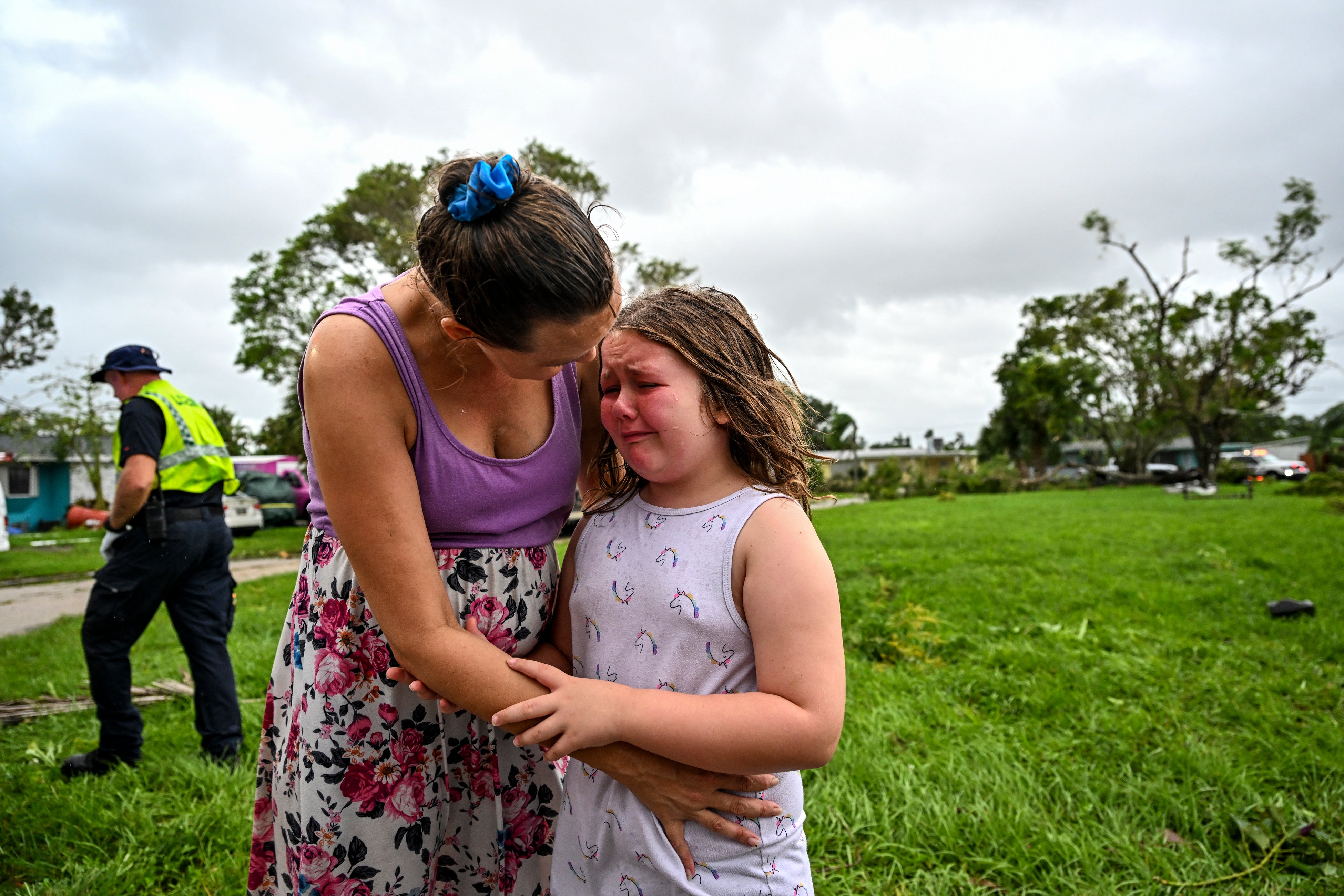Samantha Dubberly comforts her daughter as medics treat her grandfather who was injured when a tornado struck his Fort Myers home.