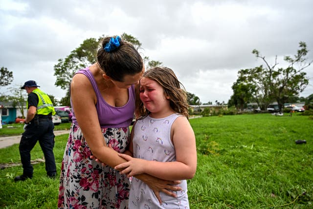 <p>Samantha Dubberly consoles her daughter as medics takes her grandfather into care after he got injured by a tornado that hit his house in Fort Myers, Florida, during Hurricane Milton </p>
