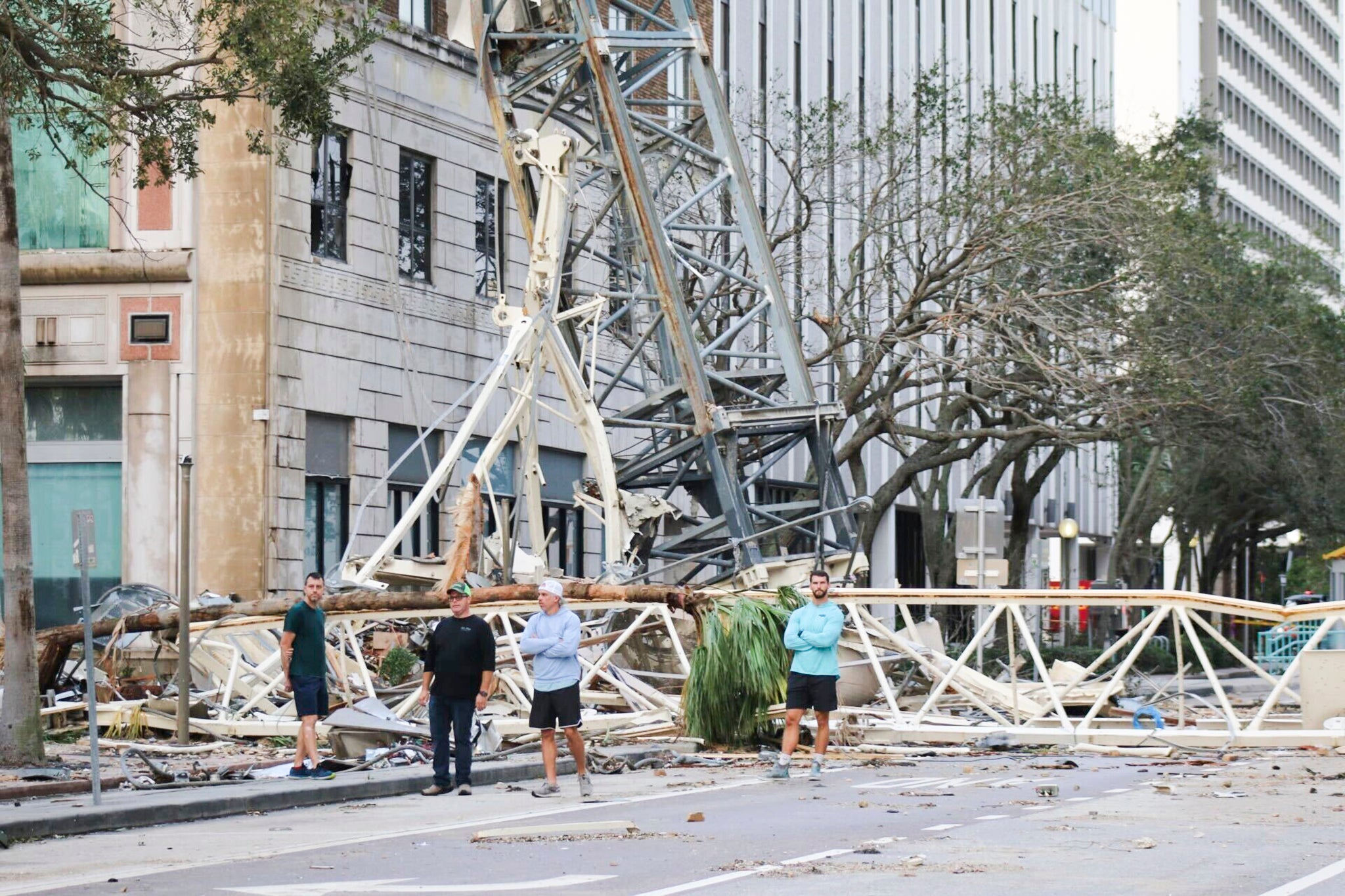 People stand around the twisted metal and rubble from the building