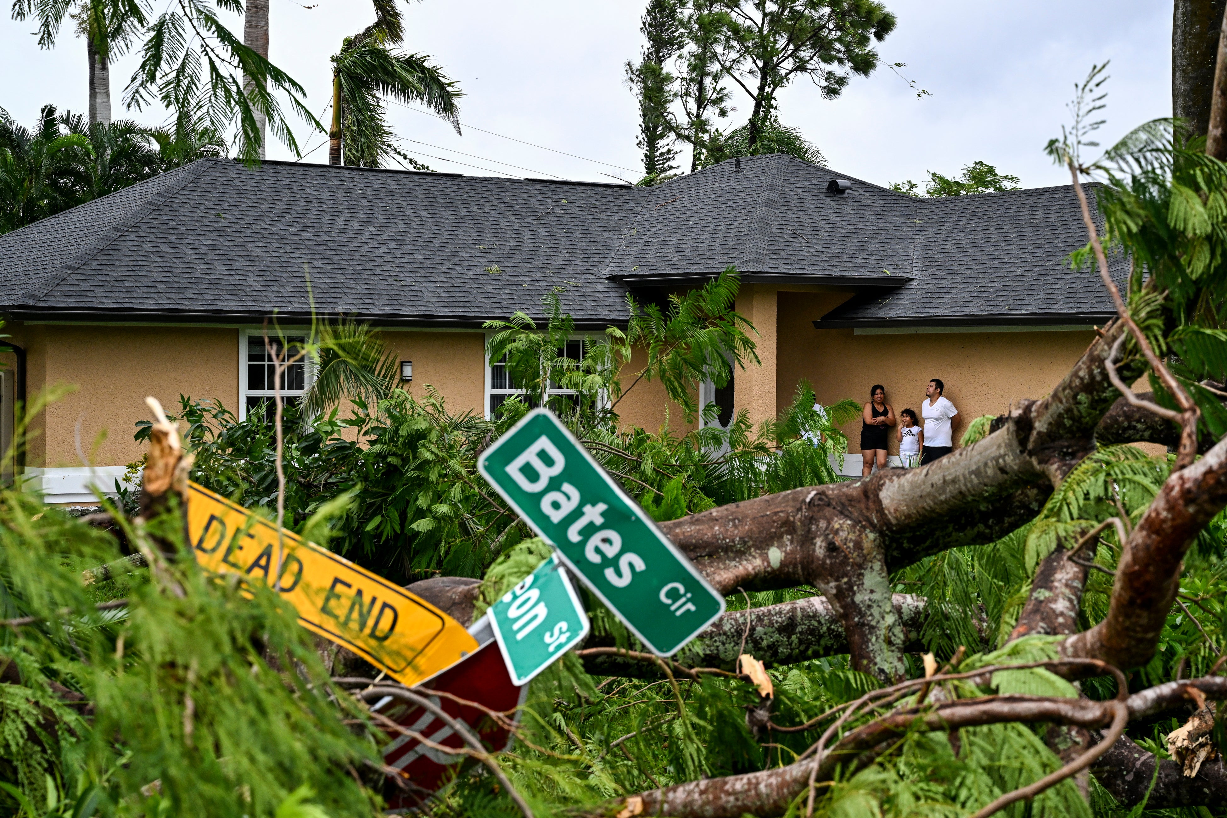 Oscar Garcia, right, stands outside his family’s home after his Fort Myers neighborhood was battered by a tornado. Milton spawned several tornados and hundreds of warnings. The tornados have been blamed for at least four deaths