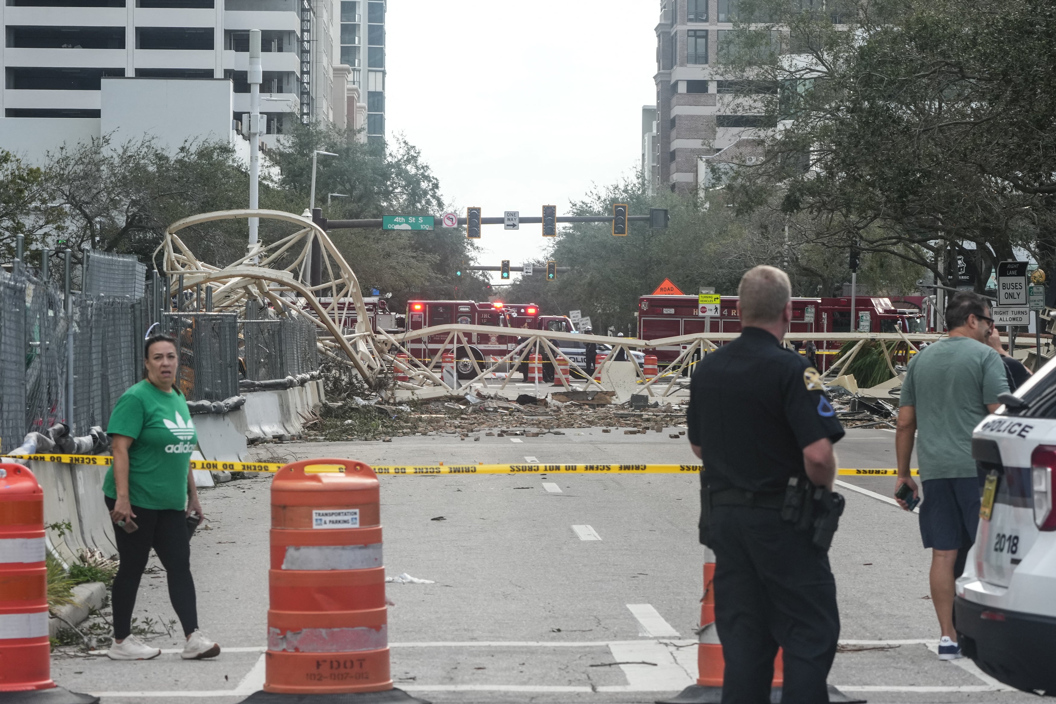 A police officer observes a collapsed crane in front of the office building. Officials have cordoned off the area to prevent injuries. Florida is now spending the day assessing the damage and starting to pick up the pieces