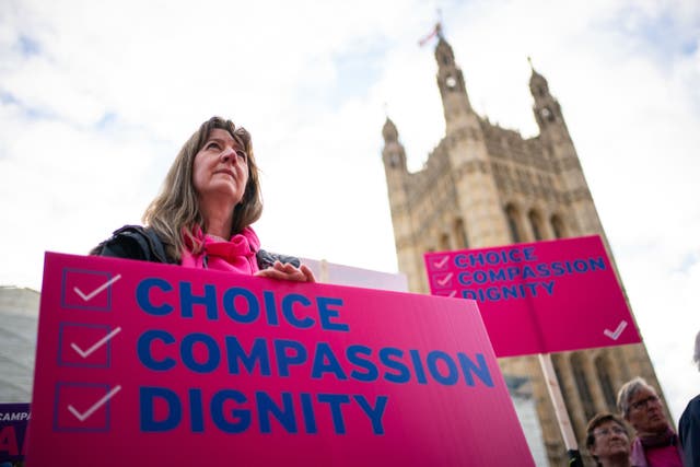 <p>A woman with a pro-assisted dying placard outside parliament</p>