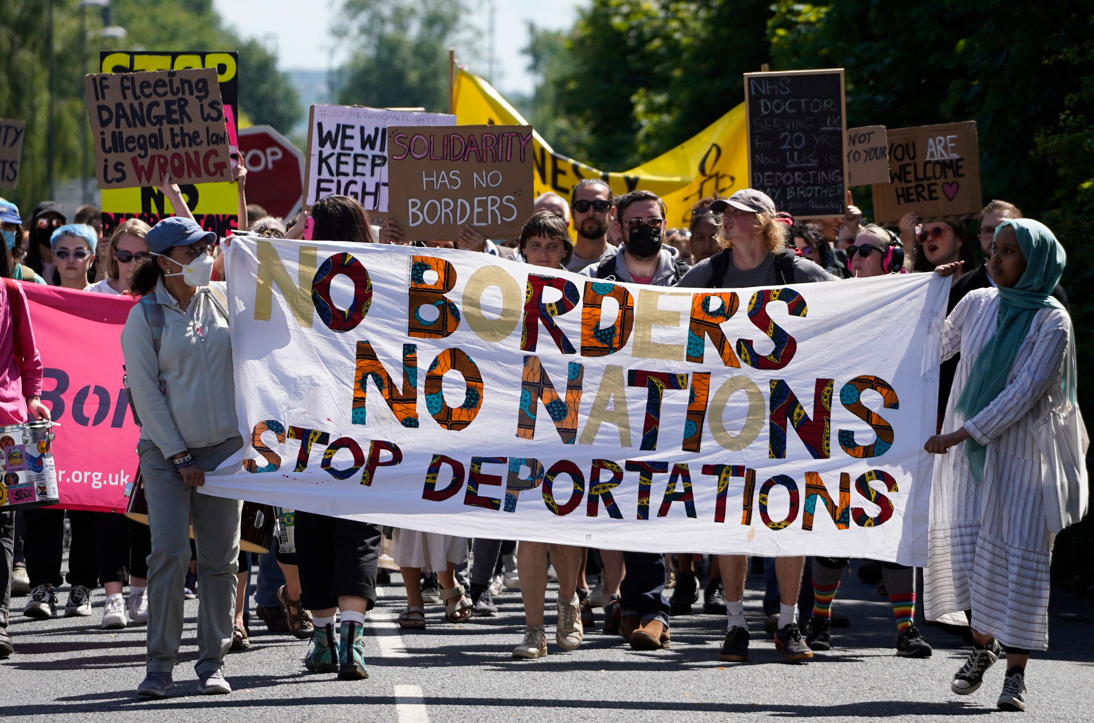 Protesters hold up placards as they march towards the Brook House immigration removal centre, which is also part of the immigration centre besides Gatwick Airport, south of London