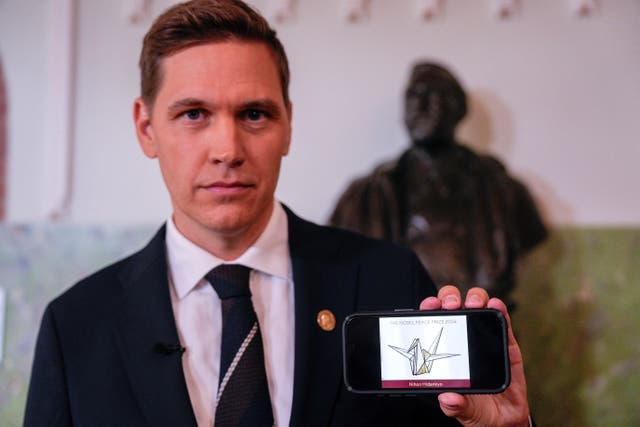 <p>The head of the Norwegian Nobel Committee, Joergen Watne Frydnes, holds a mobile phone displaying an illustration with the name of the 2024 Nobel Peace Prize winner, the Japanese organisation Nihon Hidankyo, in Oslo, Norway</p>