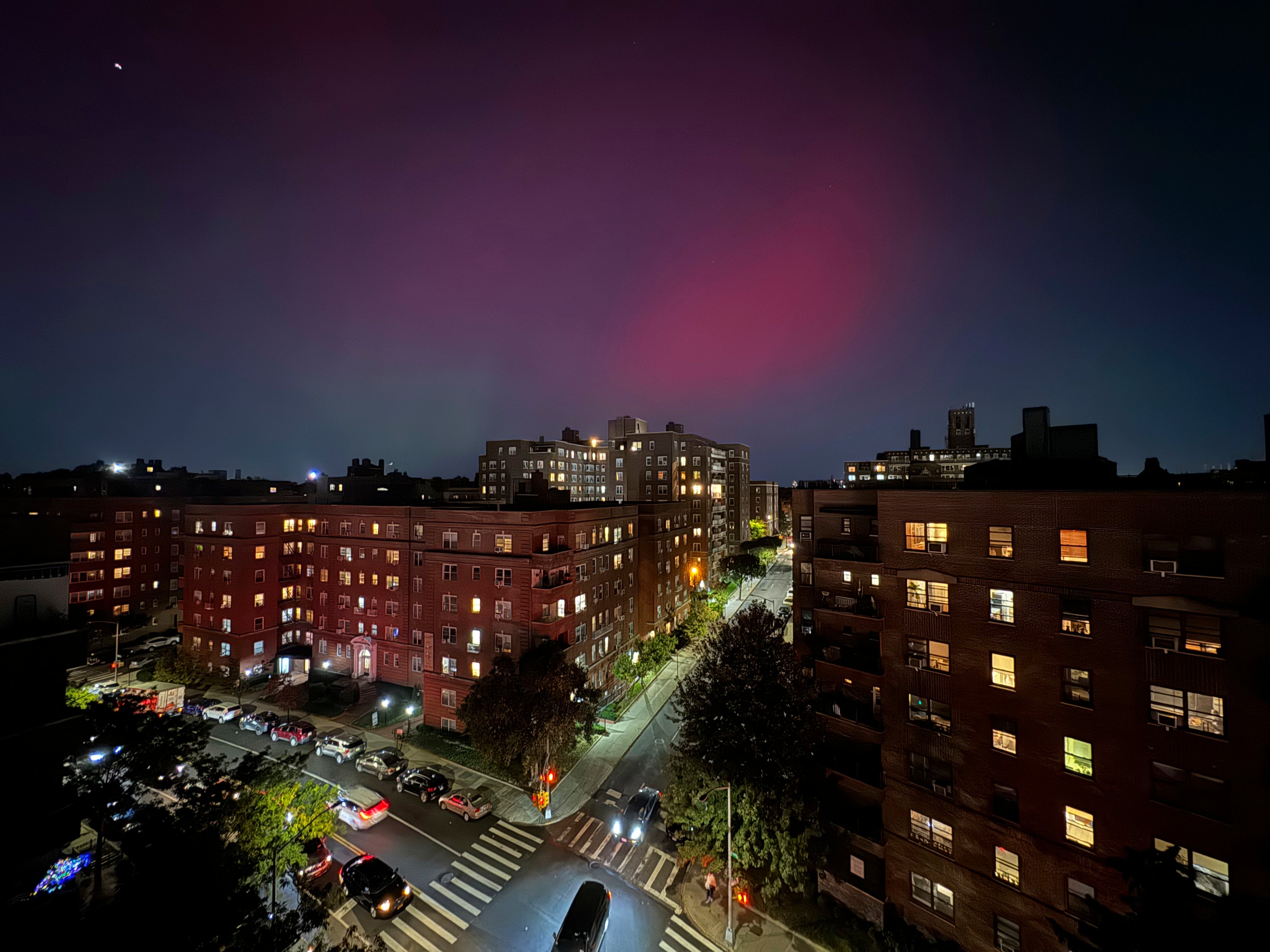 An aurora borealis, also known as the northern lights, glows in the night sky above apartment buildings in the Queens borough of New York, Thursday, Oct. 10, 2024