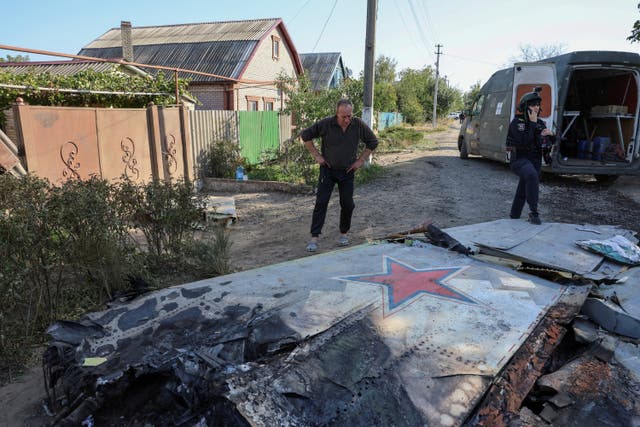 Місцевий житель дивиться на частину російського літального апарату, який місцева влада вважає новітнім важким безпілотним літальним апаратом С-70 «Охотник» (Hanter) (через REUTERS)