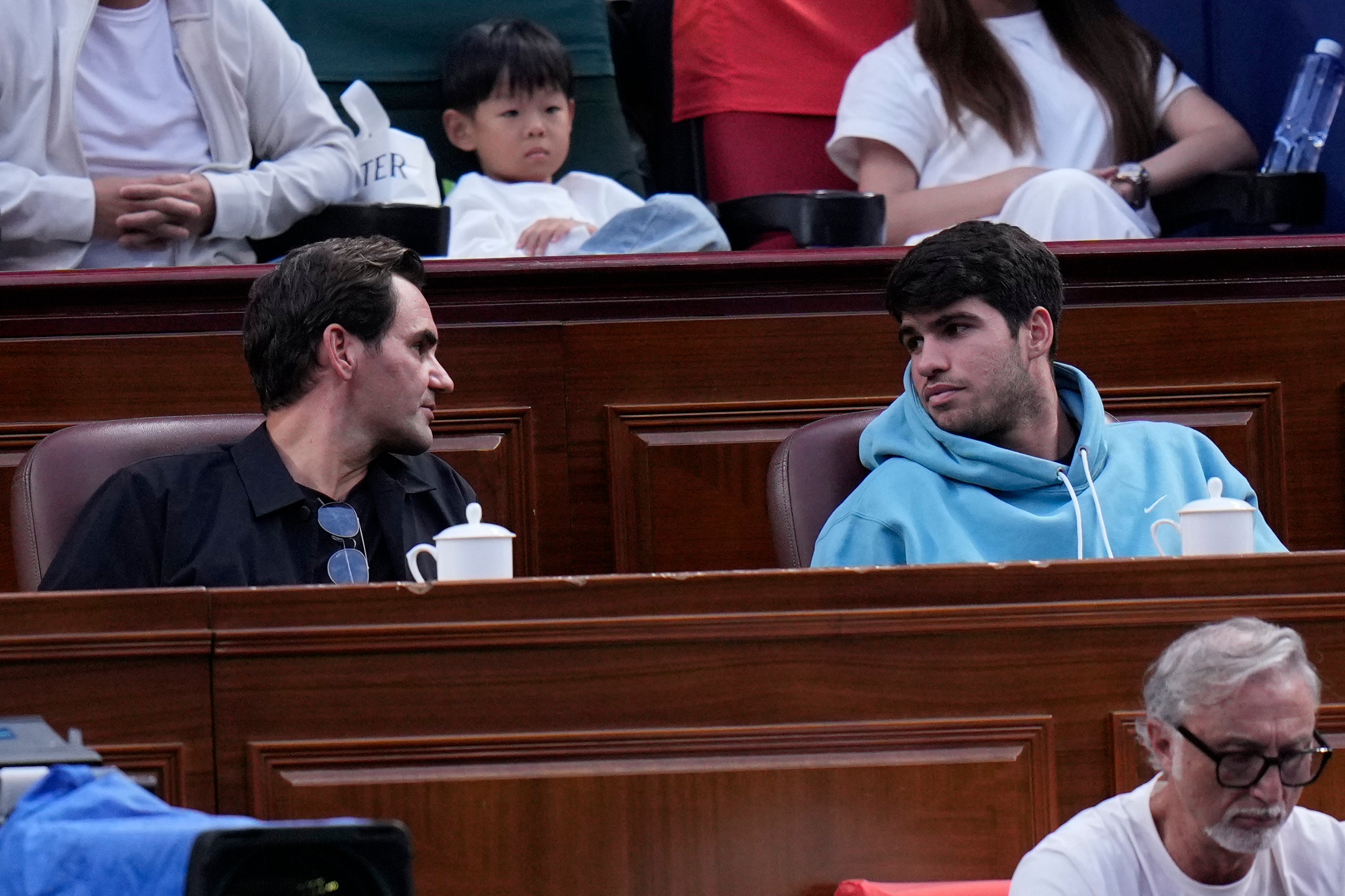 Roger Federer, left talks to Carlos Alcaraz in the stands (Andy Wong/AP)