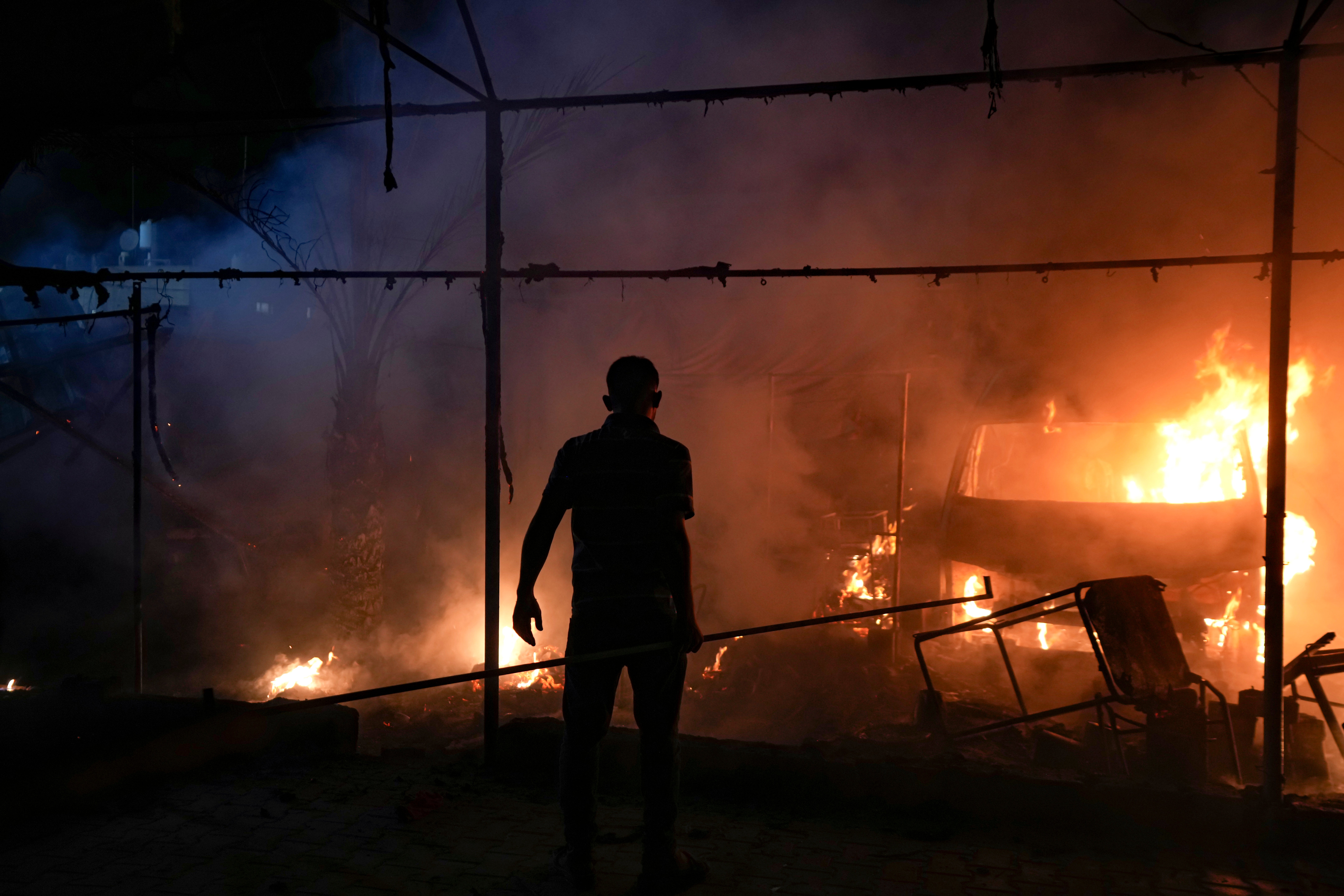 A Palestinian man reacts to a fire after an Israeli strike hit a tent area in the courtyard of Al Aqsa Martyrs hospital