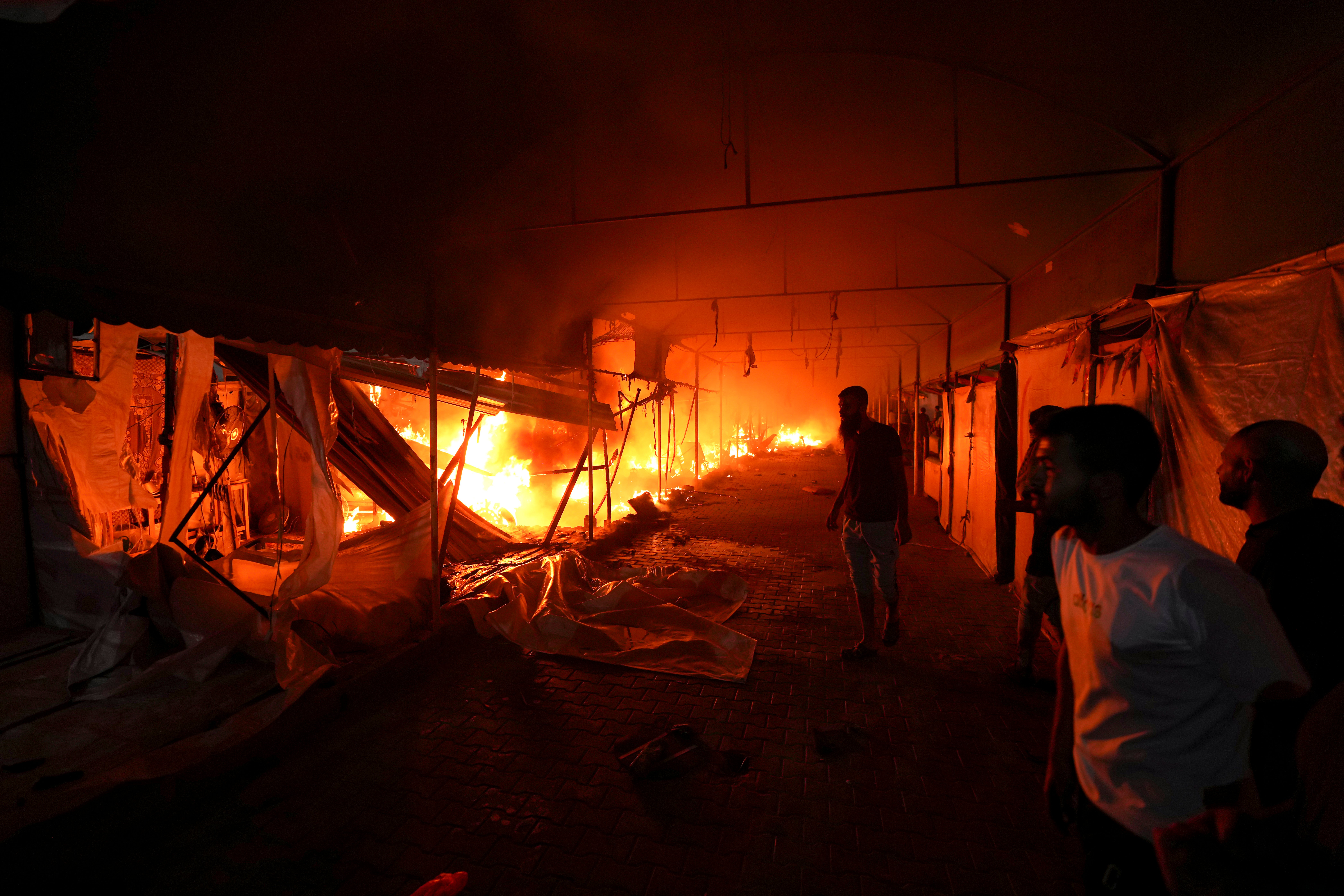 Palestinians react to a fire after an Israeli strike hit a tent area in the courtyard of Al Aqsa Martyrs hospital