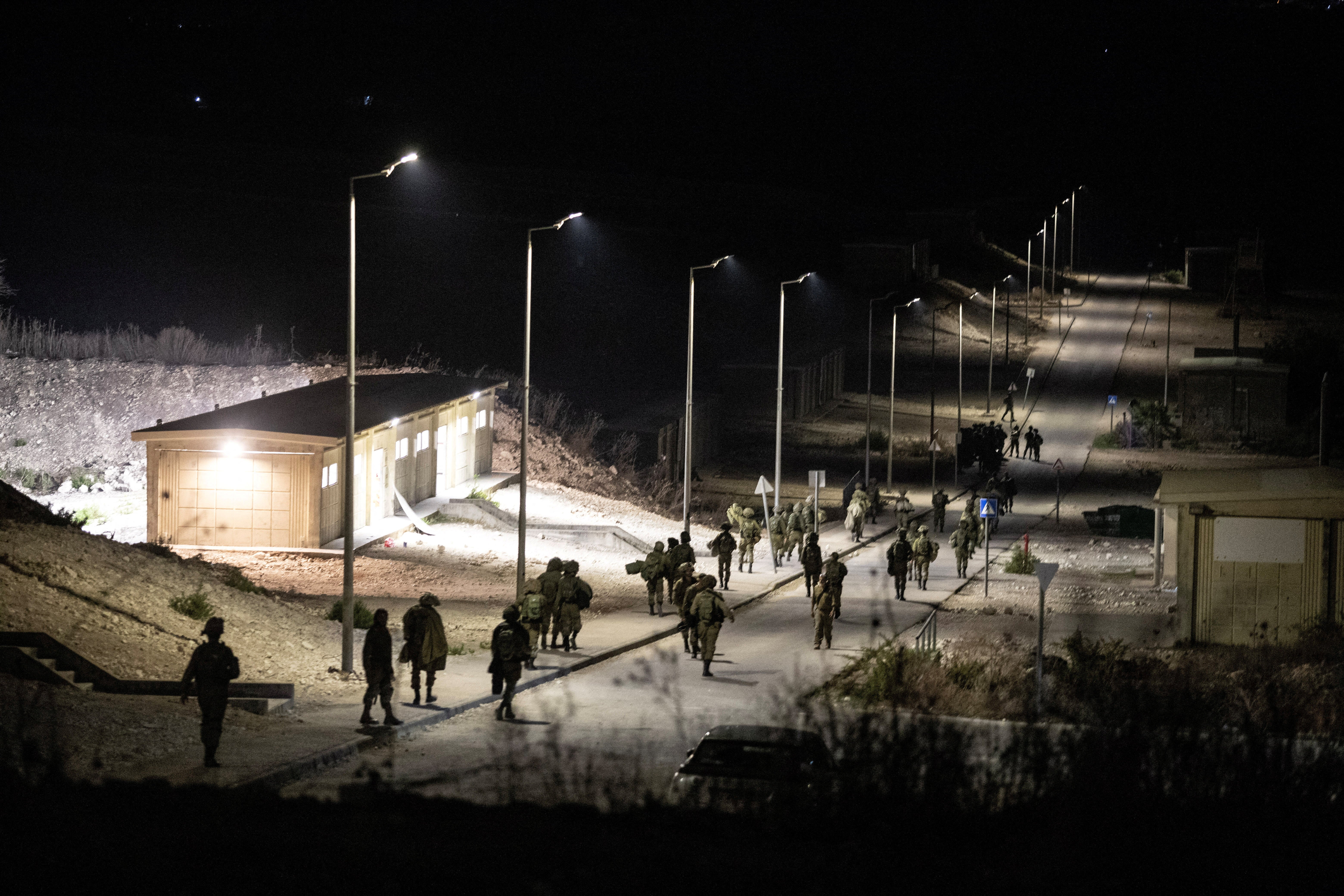 Israeli soldiers walk near the site where Hezbollah drones launched from southern Lebanon hit Israel on Sunday