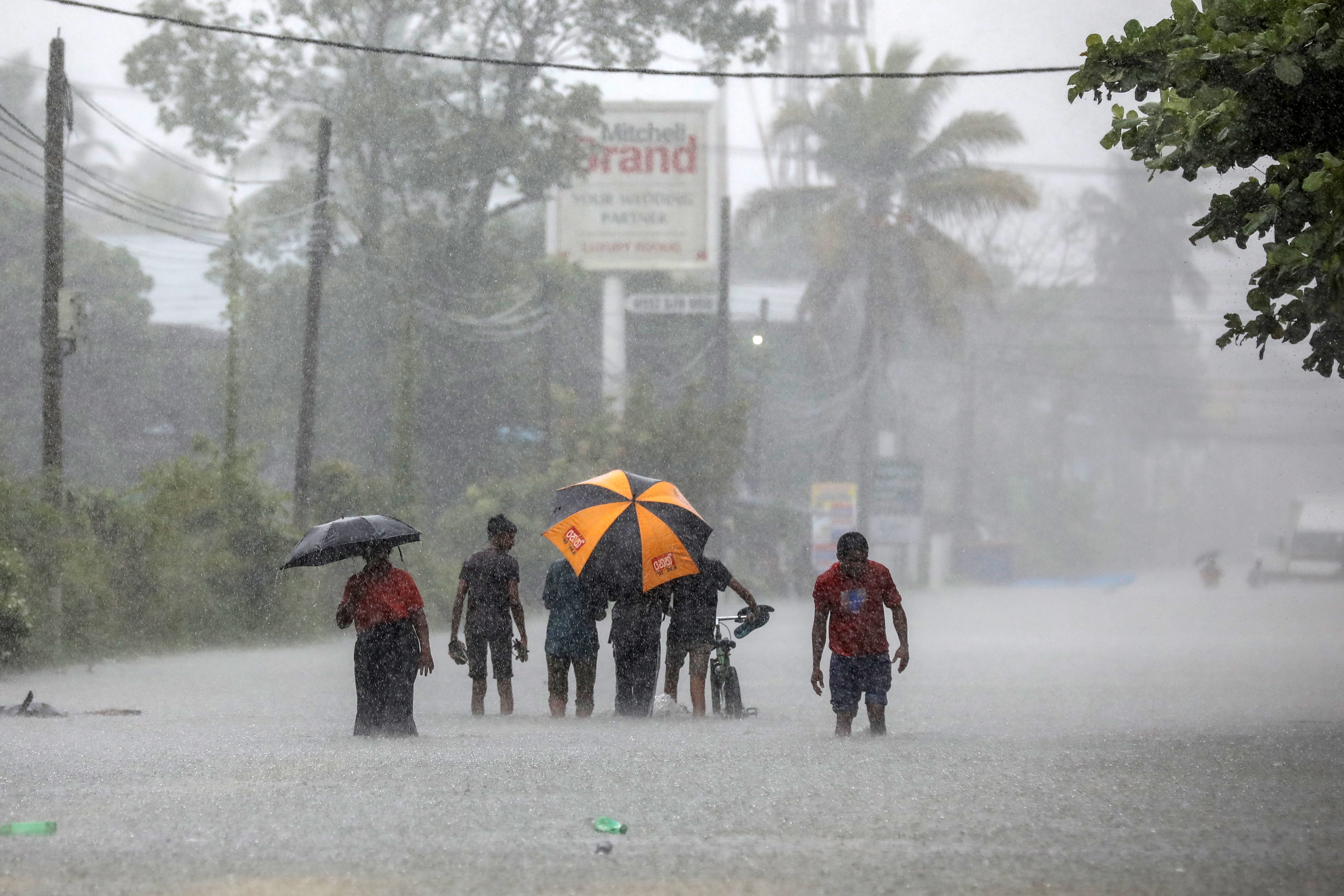 People walk along a flooded road after heavy rainfall in Colombo, Sri Lanka