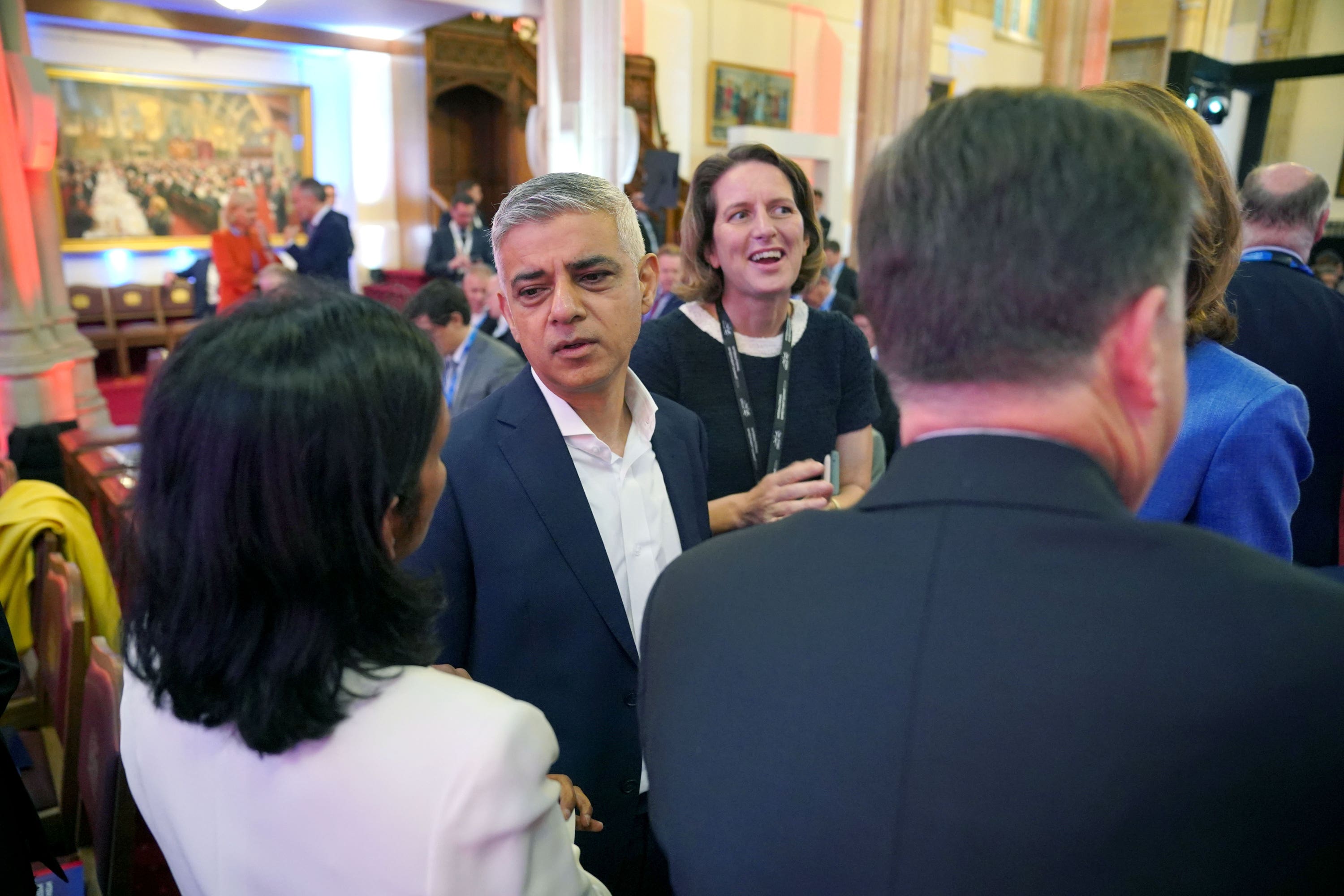 Khan speaks with guests at the international investment summit in London on Monday