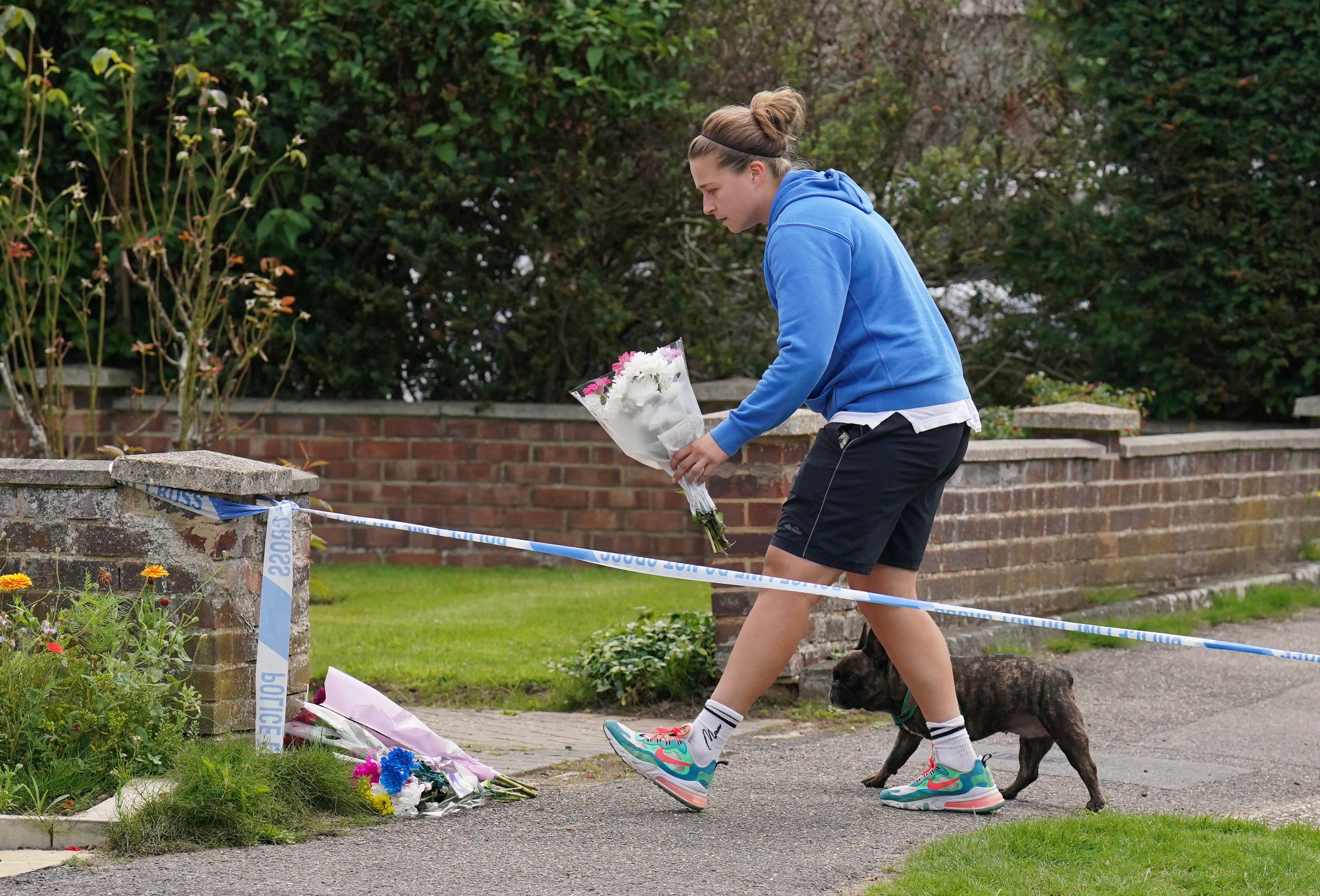 A person leaves flowers outside a property on Hammond Road in Woking, Surrey, where Sara Sharif was found dead