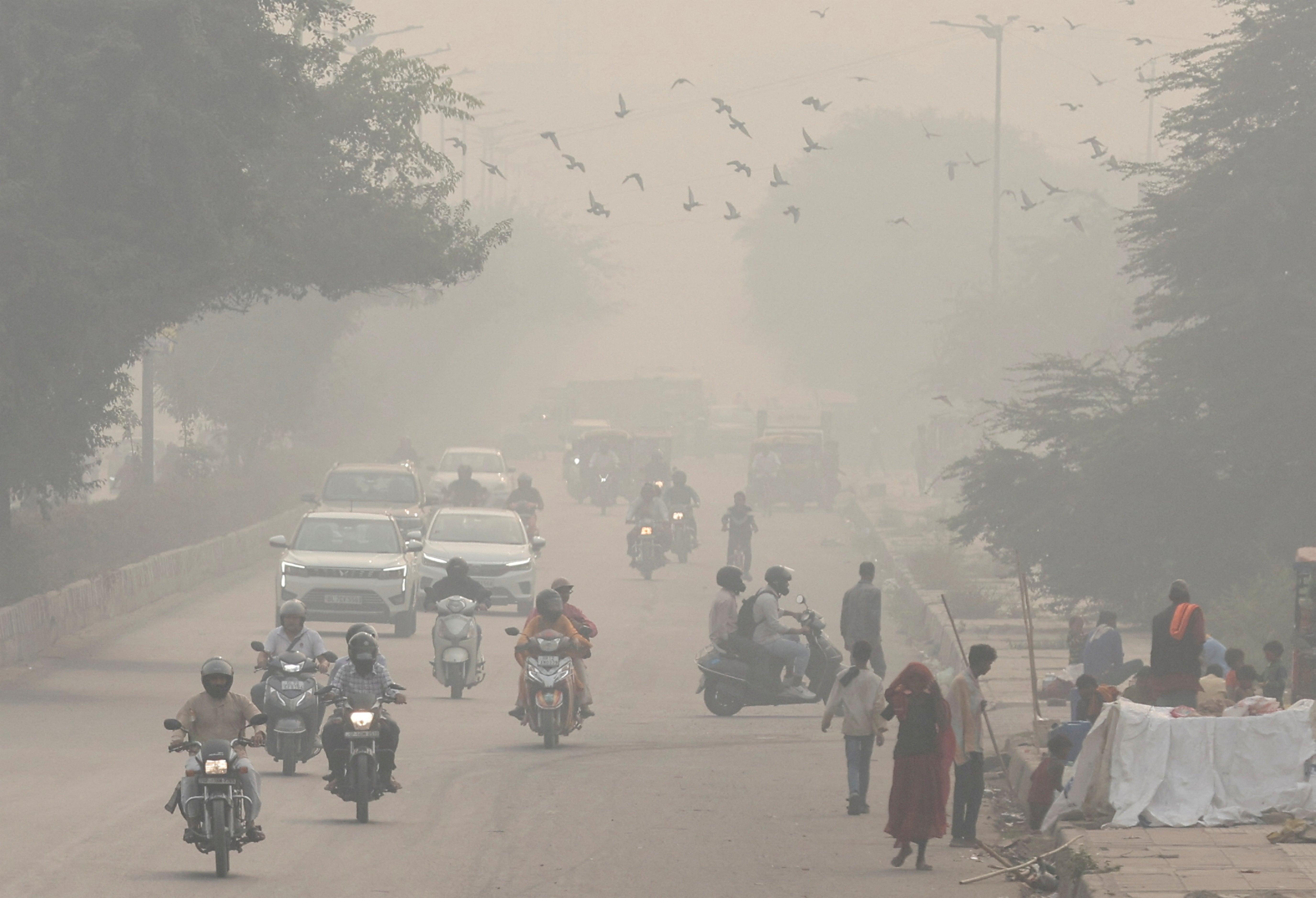 <p>File: People and vehicles are seen on a road amidst the morning smog in New Delhi, India, 8 November 2023</p>