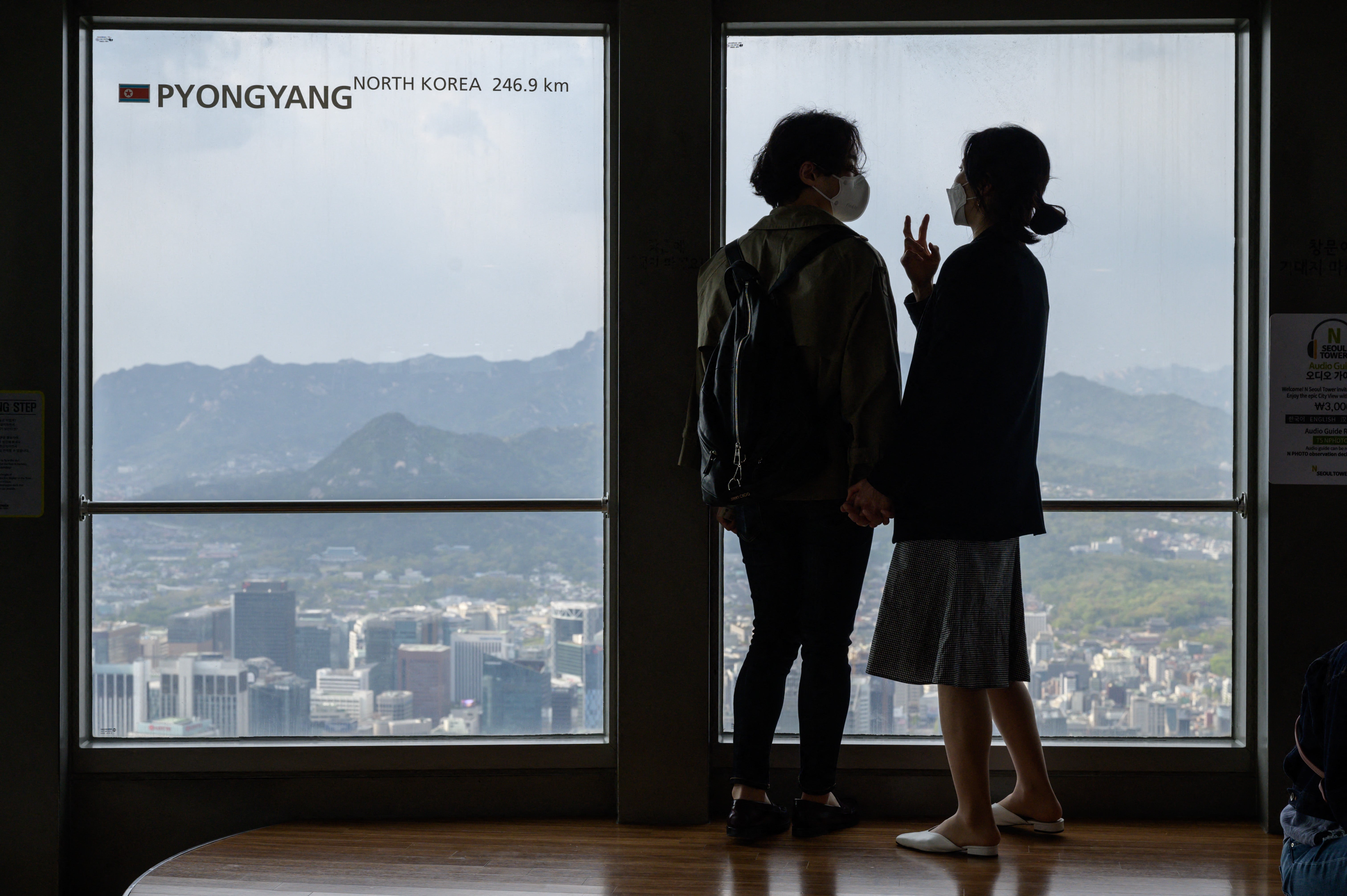 A couple stand before a window displaying the distance to the North Korean capital, Pyongyang, at the Namsan tower in South Korea