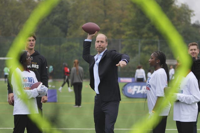 The Prince of Wales throws a football at a target (Kin Cheung/PA)