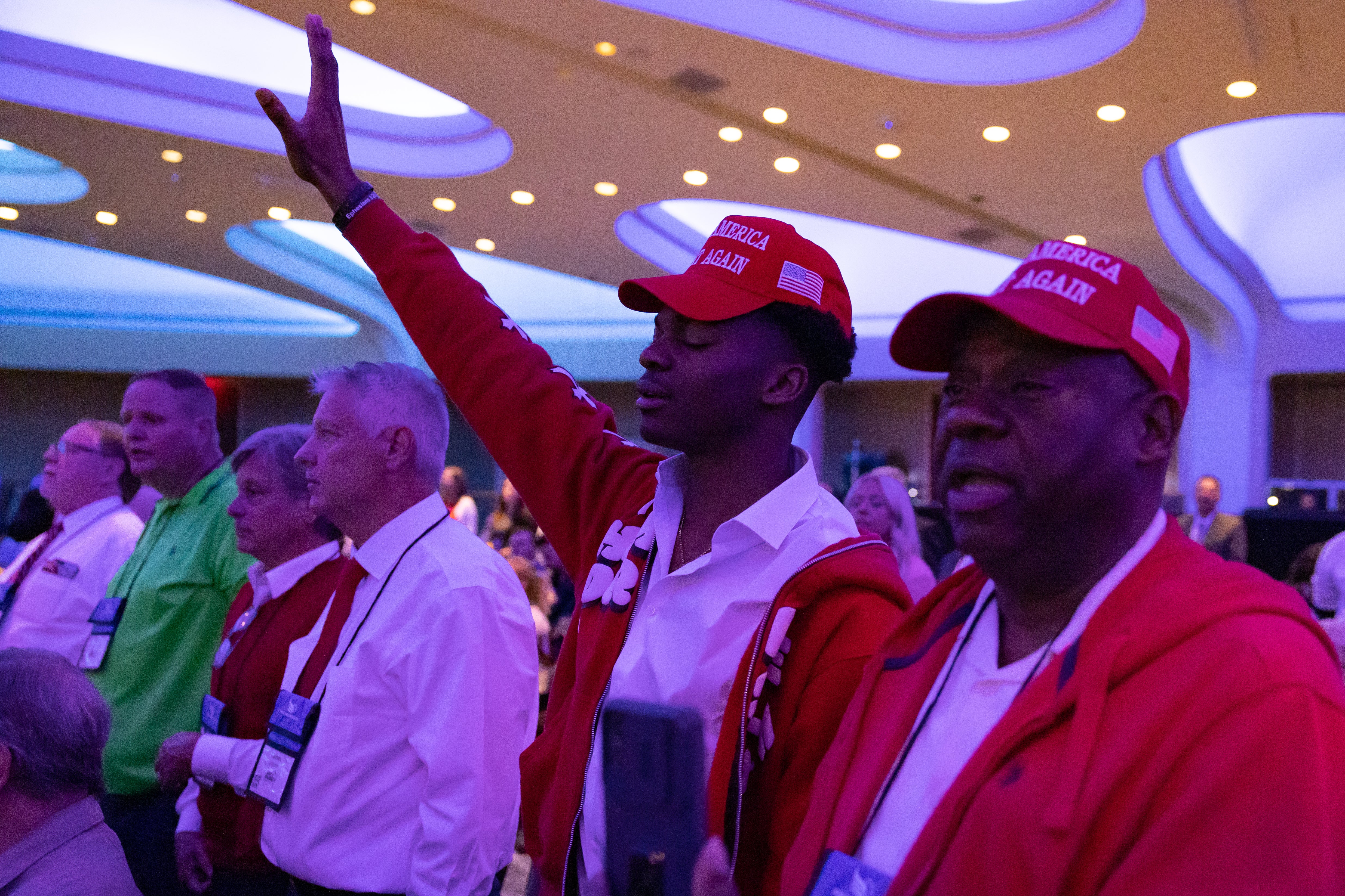 Attendees wearing MAGA hats pray at the Faith and Freedom conference in Washington DC