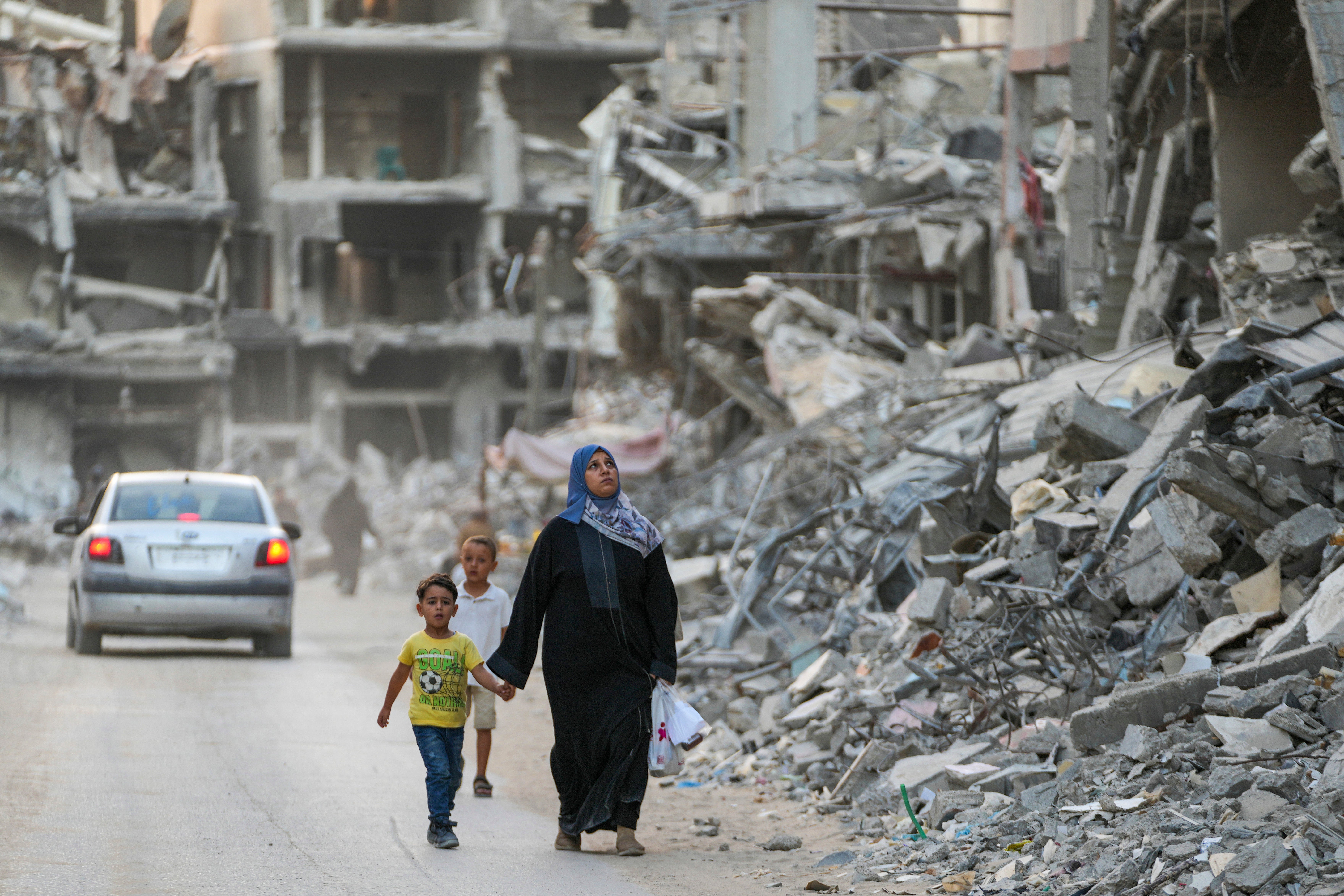 Palestinians walk through the destruction left by an Israeli air and ground offensive on Khan Younis in the Gaza Strip