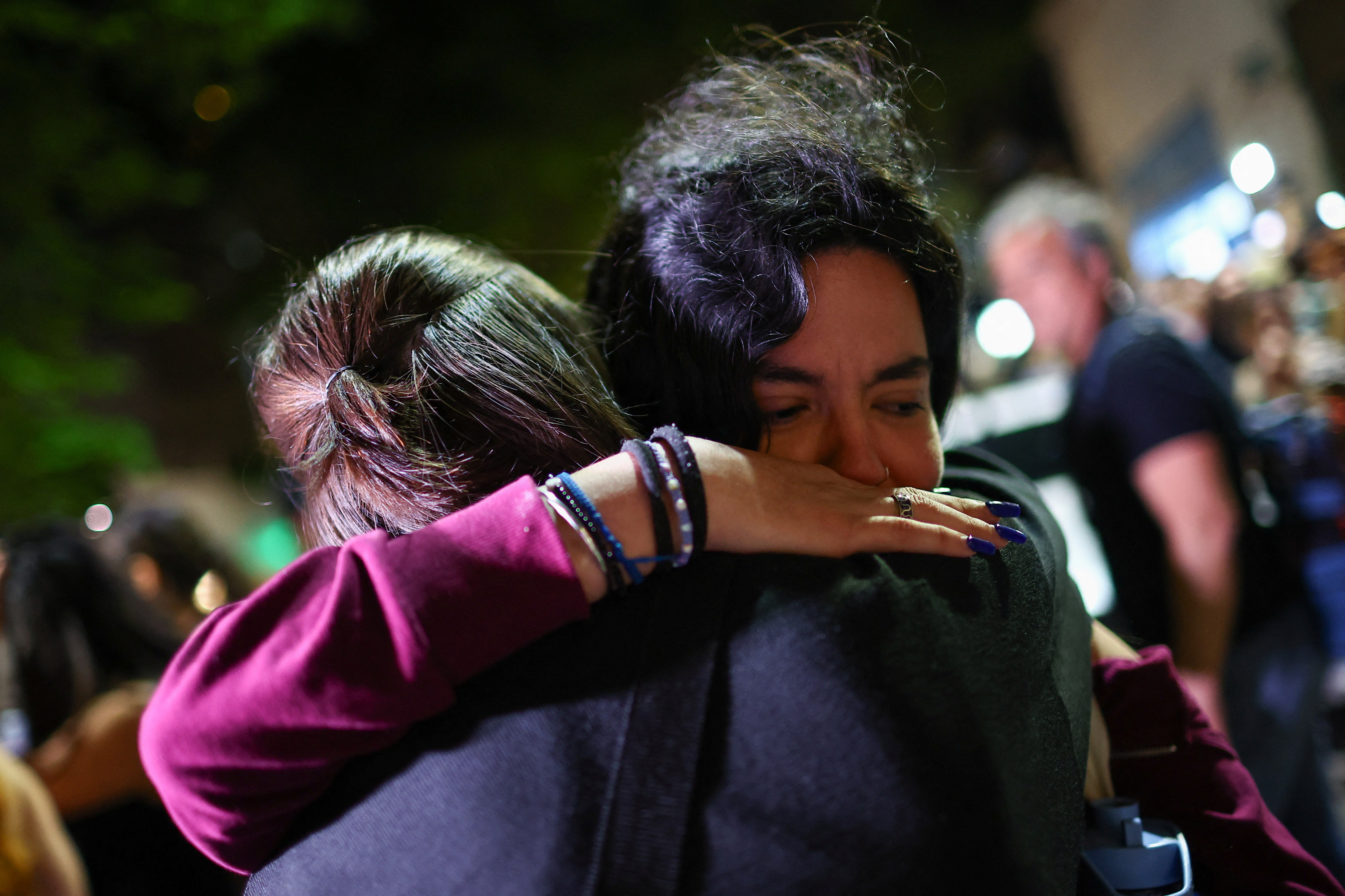 Fans hug outside the hotel where authorities found Payne's body on Wednesday evening