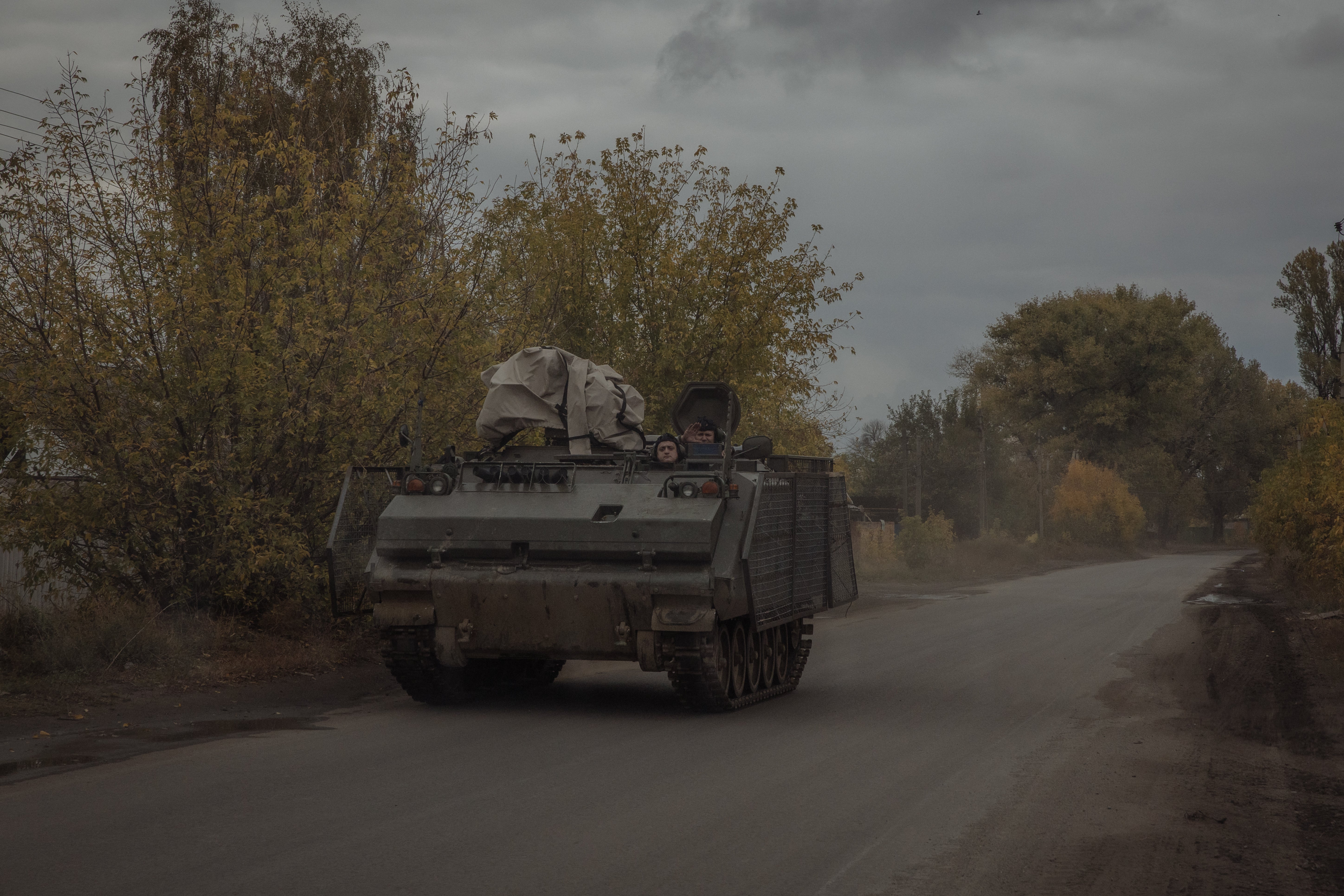 Ukrainian servicemen ride an armoured military vehicle on a road in the Donetsk region