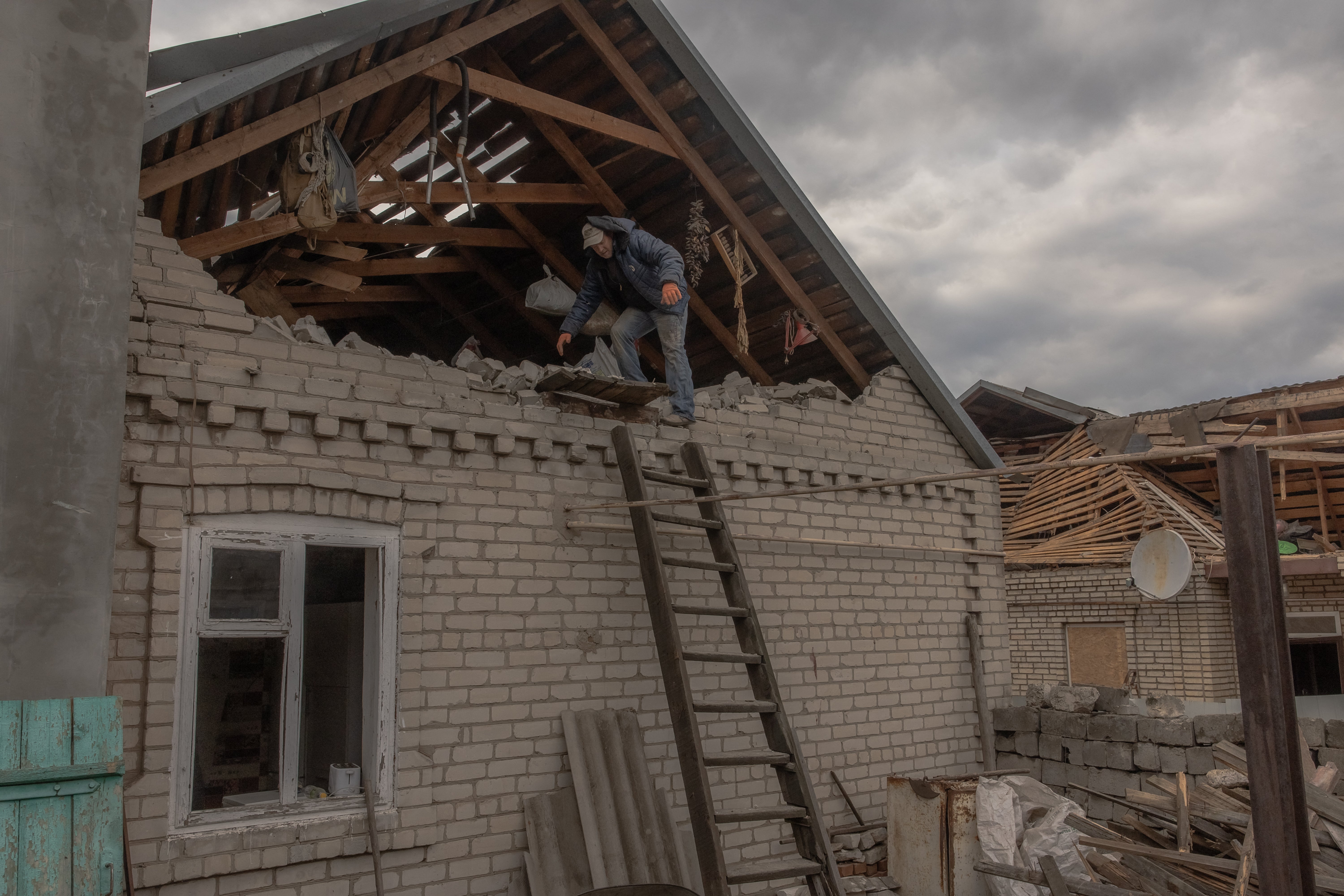 A man clears debris in a damaged house following a recent air attack in a village outside of Kostyantynivka