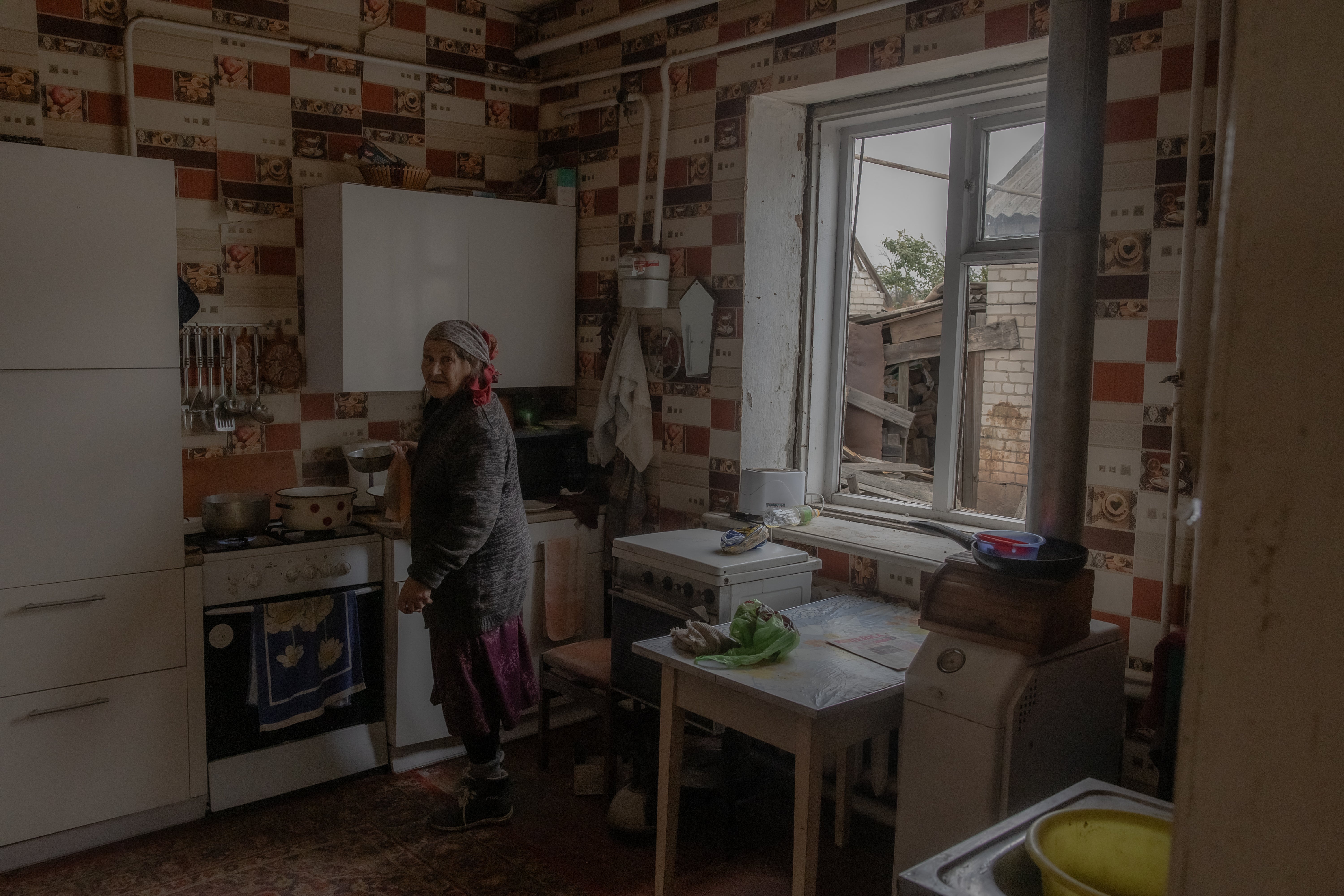 Nina, an elderly woman, cooks inside her damaged house following a recent air attack in a village outside of Kostyantynivka in the eastern Donetsk