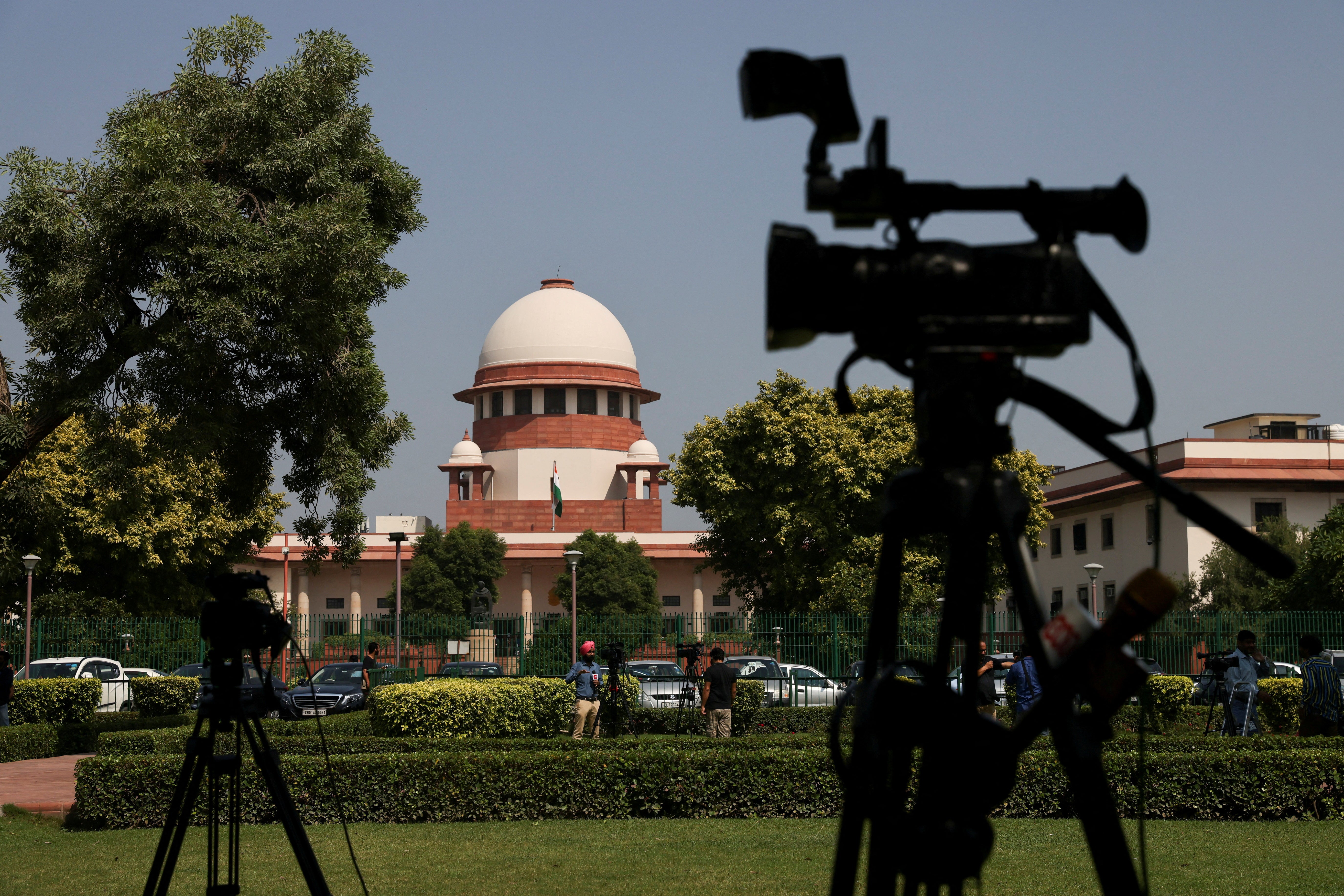 Members of media speak in front of cameras outside the premises of the Supreme Court in New Delhi, India 13 October 2022