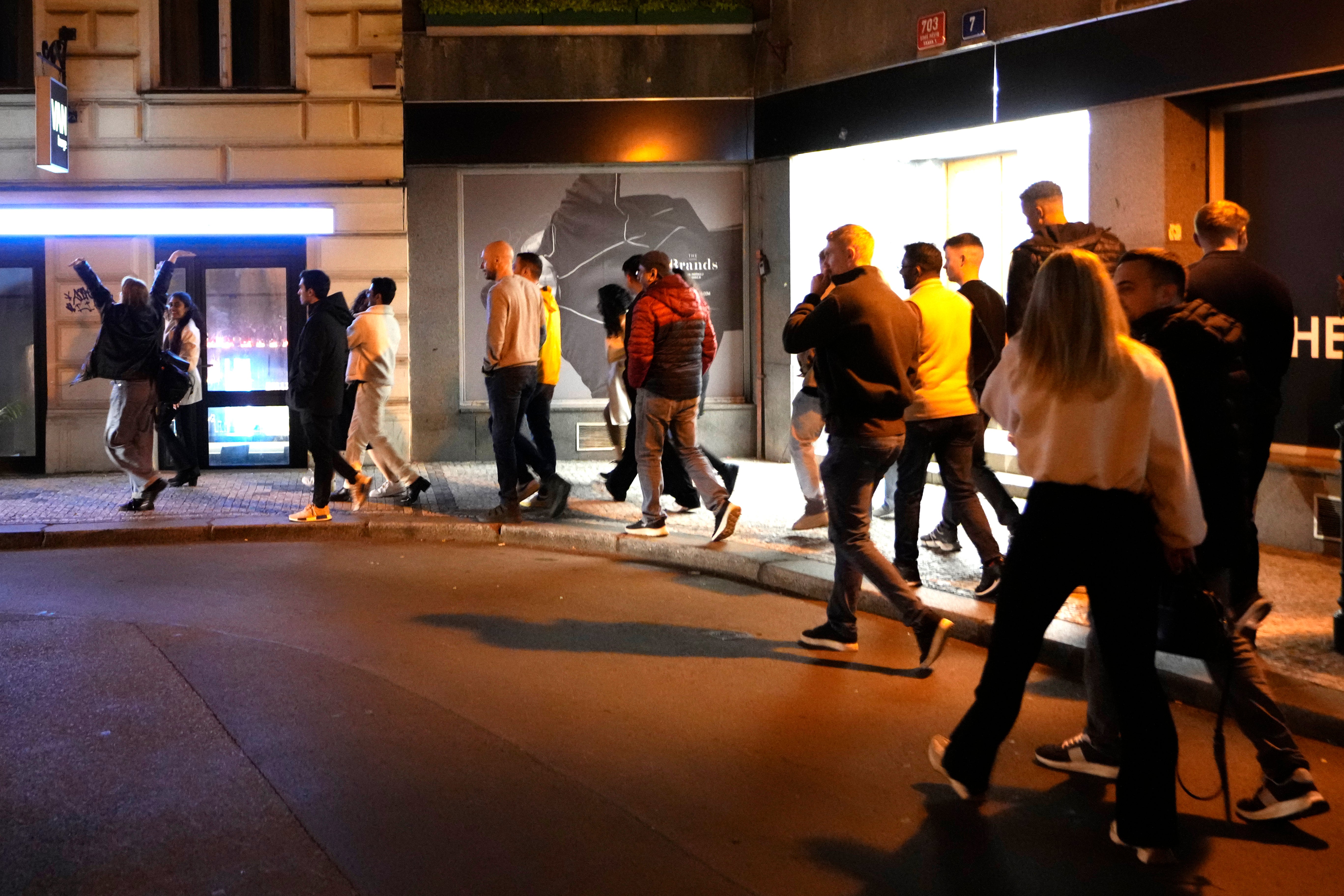 A group of tourists stand in line outside a bar as they attend a pub crawl tour in downtown Prague