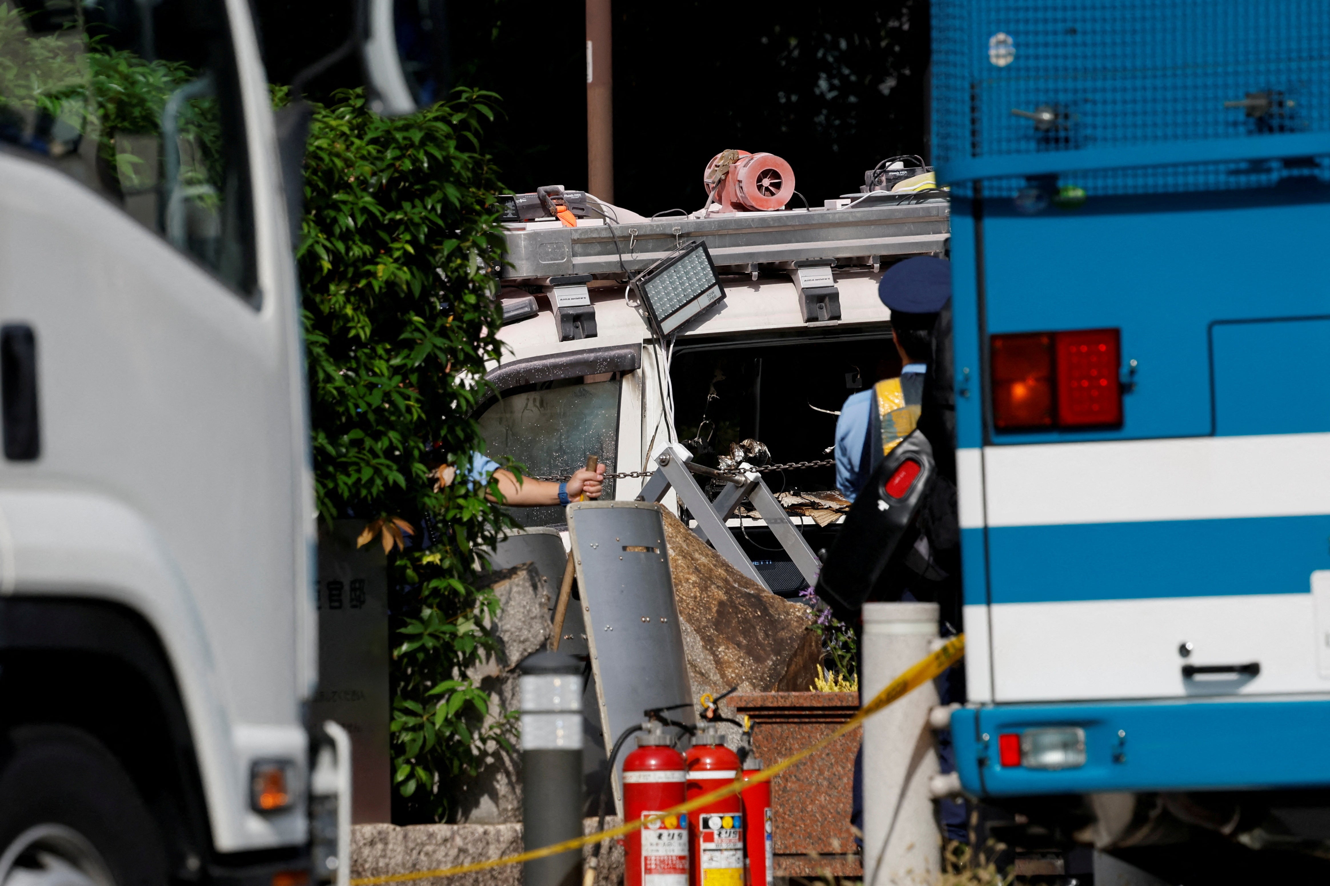 Police investigate a car stuck against a fence, near the entrance to the Prime Minister's office in Tokyo