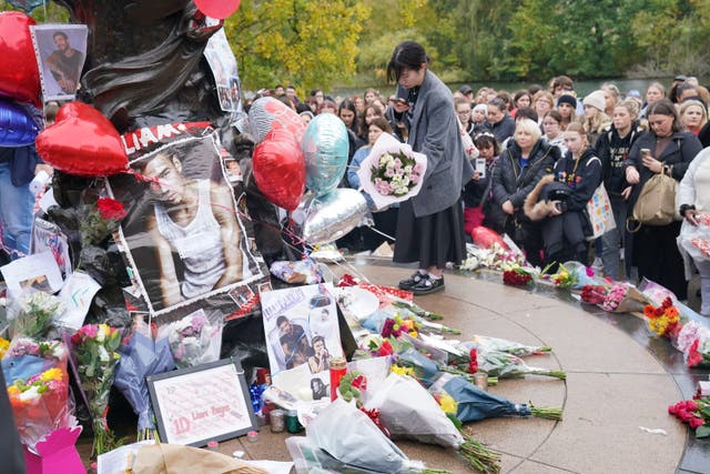 <p>A person laying flowers during a vigil for 31-year-old One Direction singer Liam Payne at Hyde Park in central London (Jonathan Brady/PA)</p>