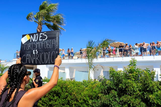 <p>Tourists watch from their hotel as demonstrators march for a change in the tourism model in the Canary Islands</p>
