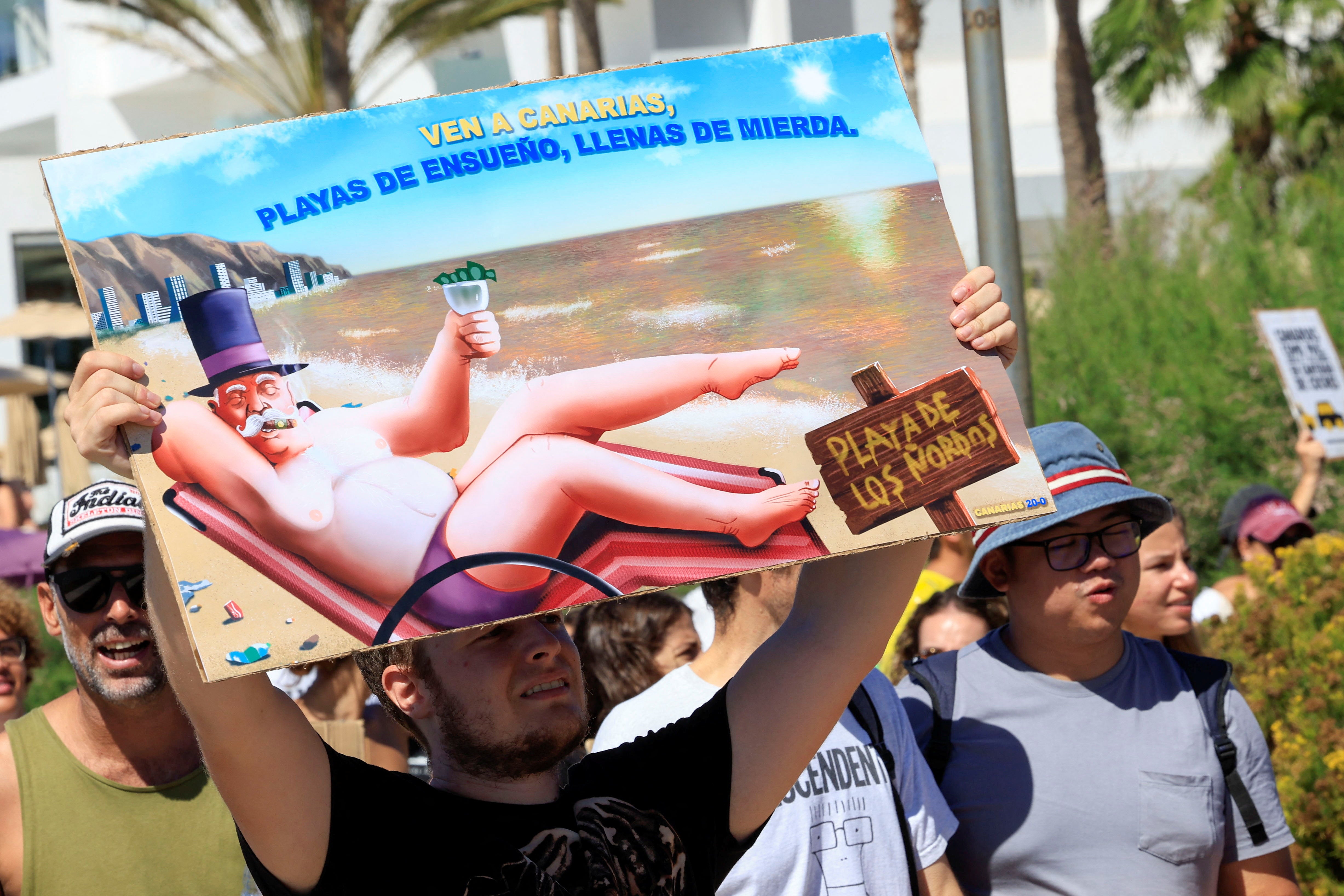 Um homem mostra uma placa durante uma manifestação pela mudança no modelo de turismo nas Ilhas Canárias, na ilha de Gran Canaria, Espanha