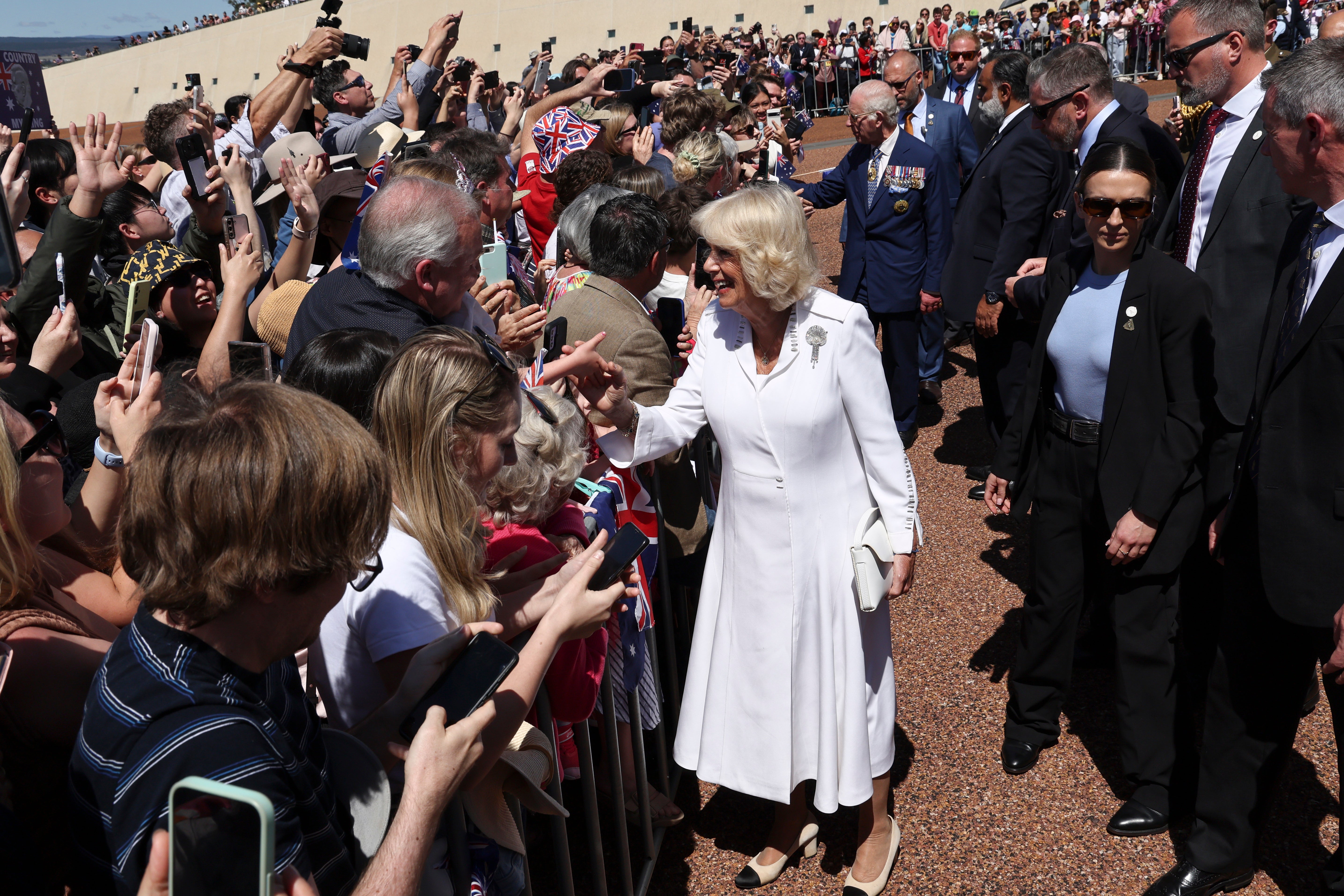 La reina Camilla de Gran Bretaña (al frente) y el rey Carlos III saludan al público frente al Parlamento en Canberra, Australia, el lunes.