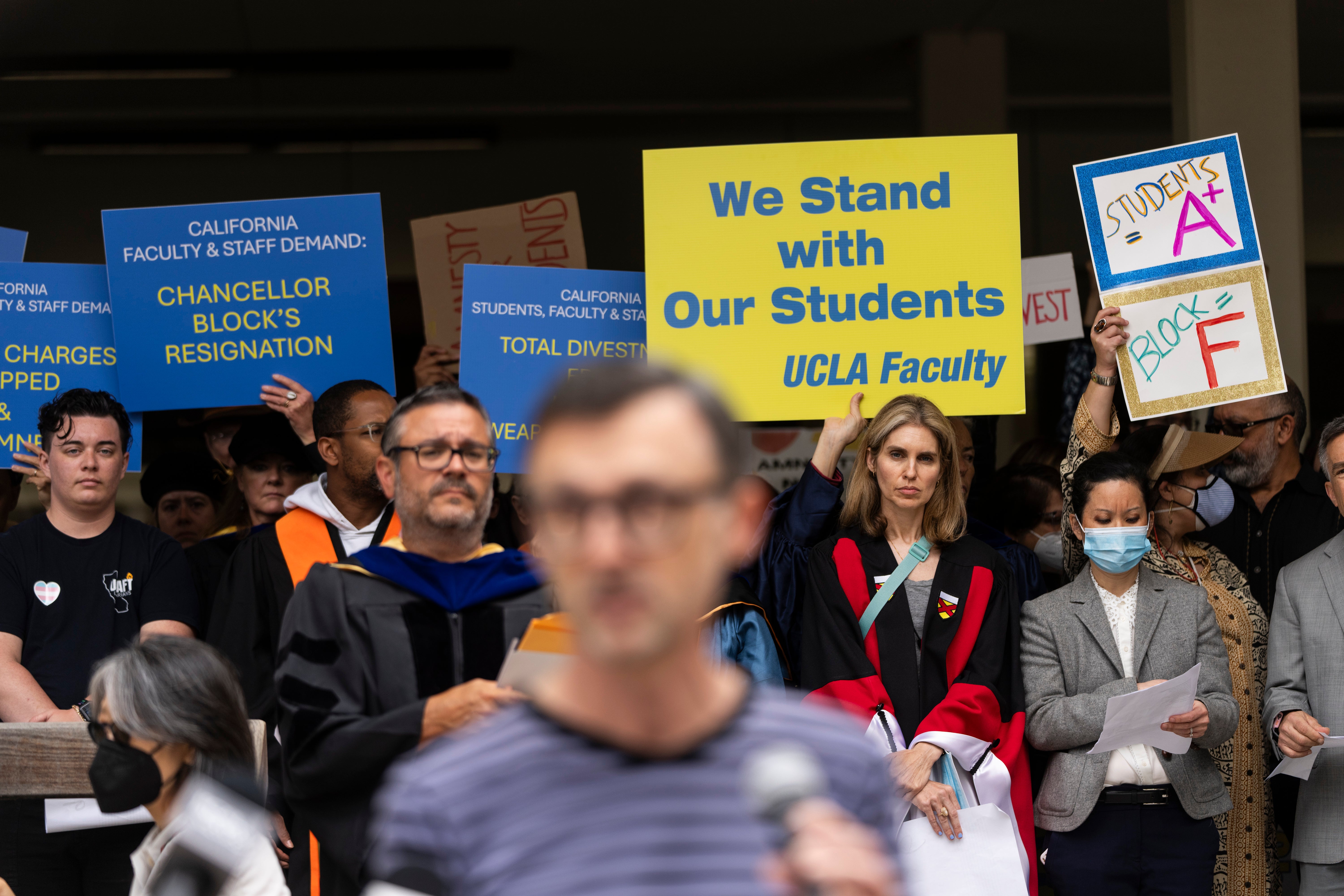 UCLA faculty and staff members hold up signs during a news conference at UCLA in Los Angeles