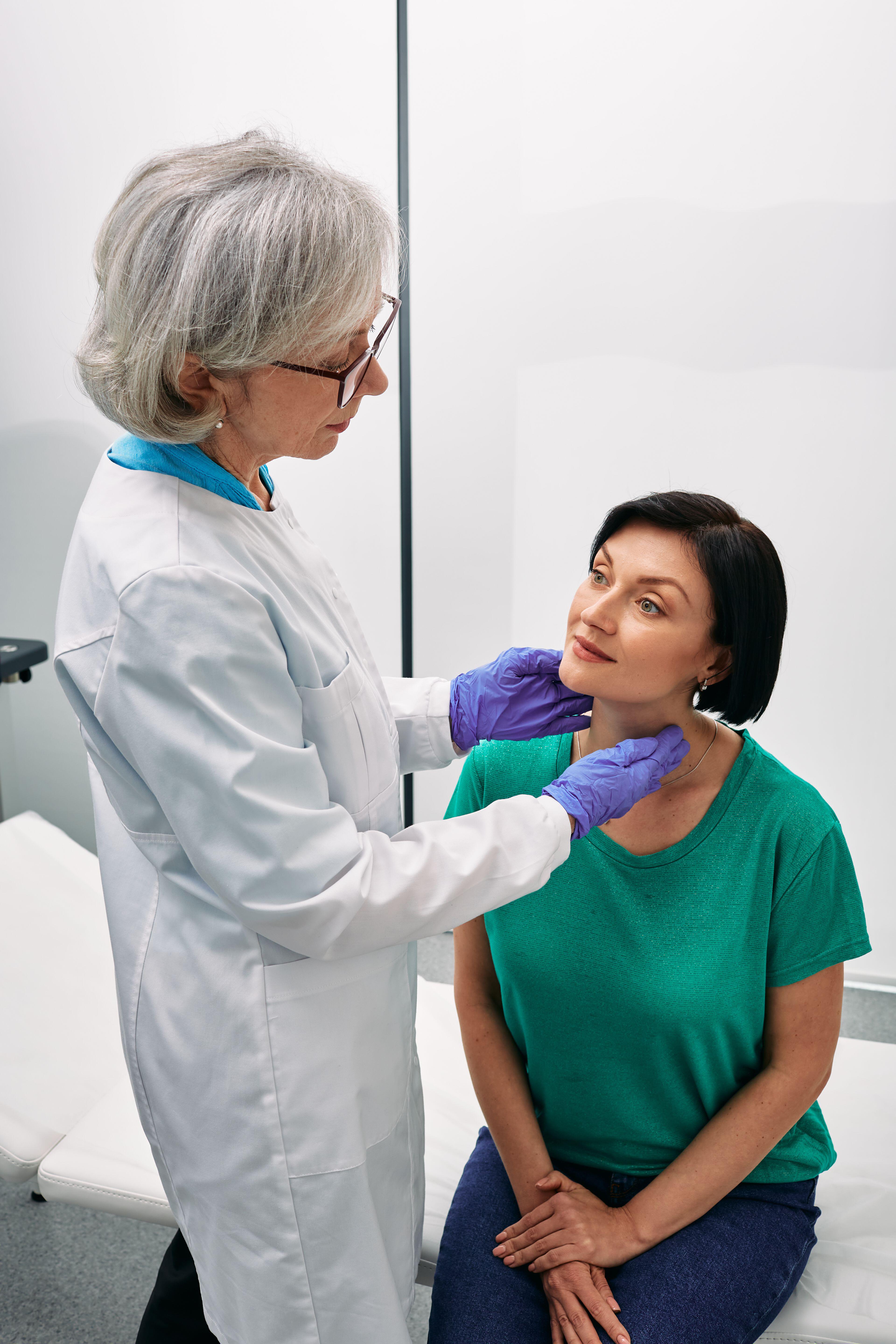 A woman having a thyroid gland examination by her doctor