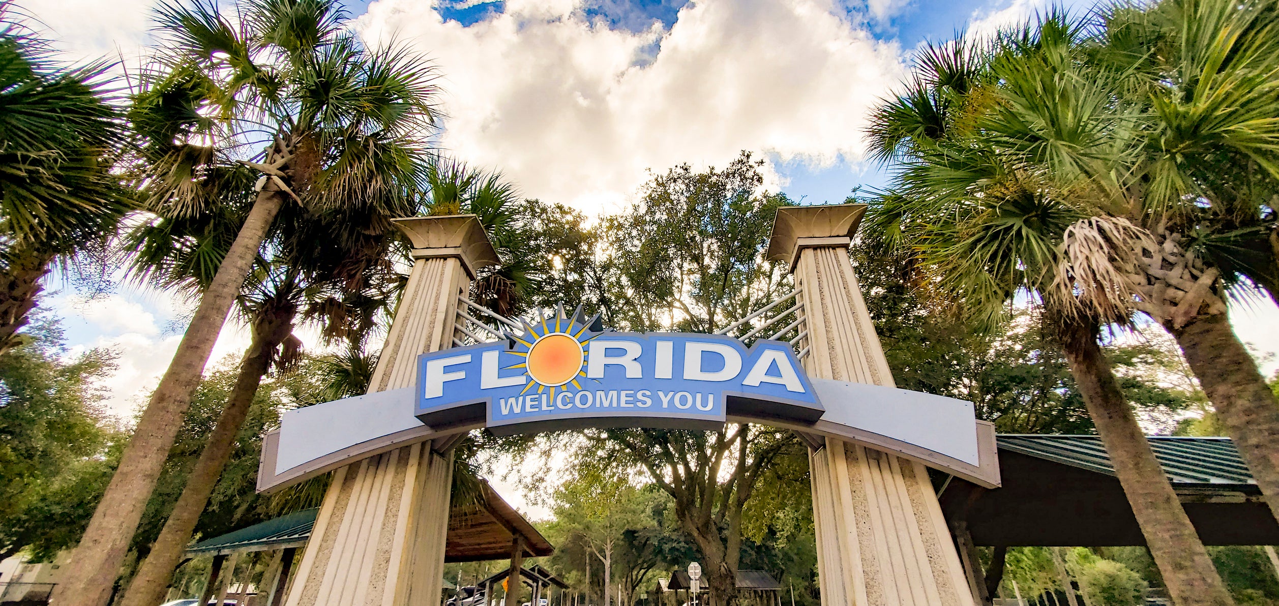 This is a photograph taken of the Welcome to Florida sign marking the state line at the border at a highway rest stop with palm trees on a sunny day with during autumn of 2020.